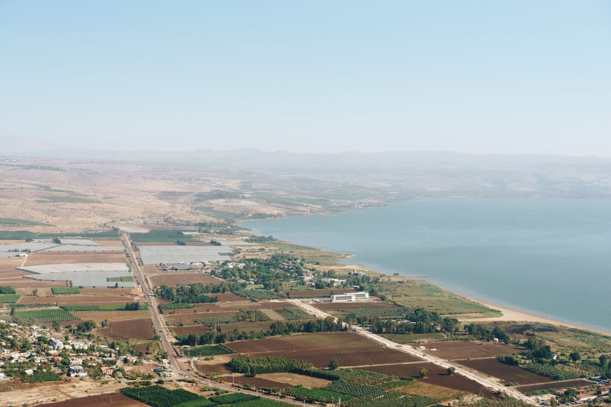 Aerial shot of farmlands and lake in North District, Israel, showcasing agriculture and landscape.