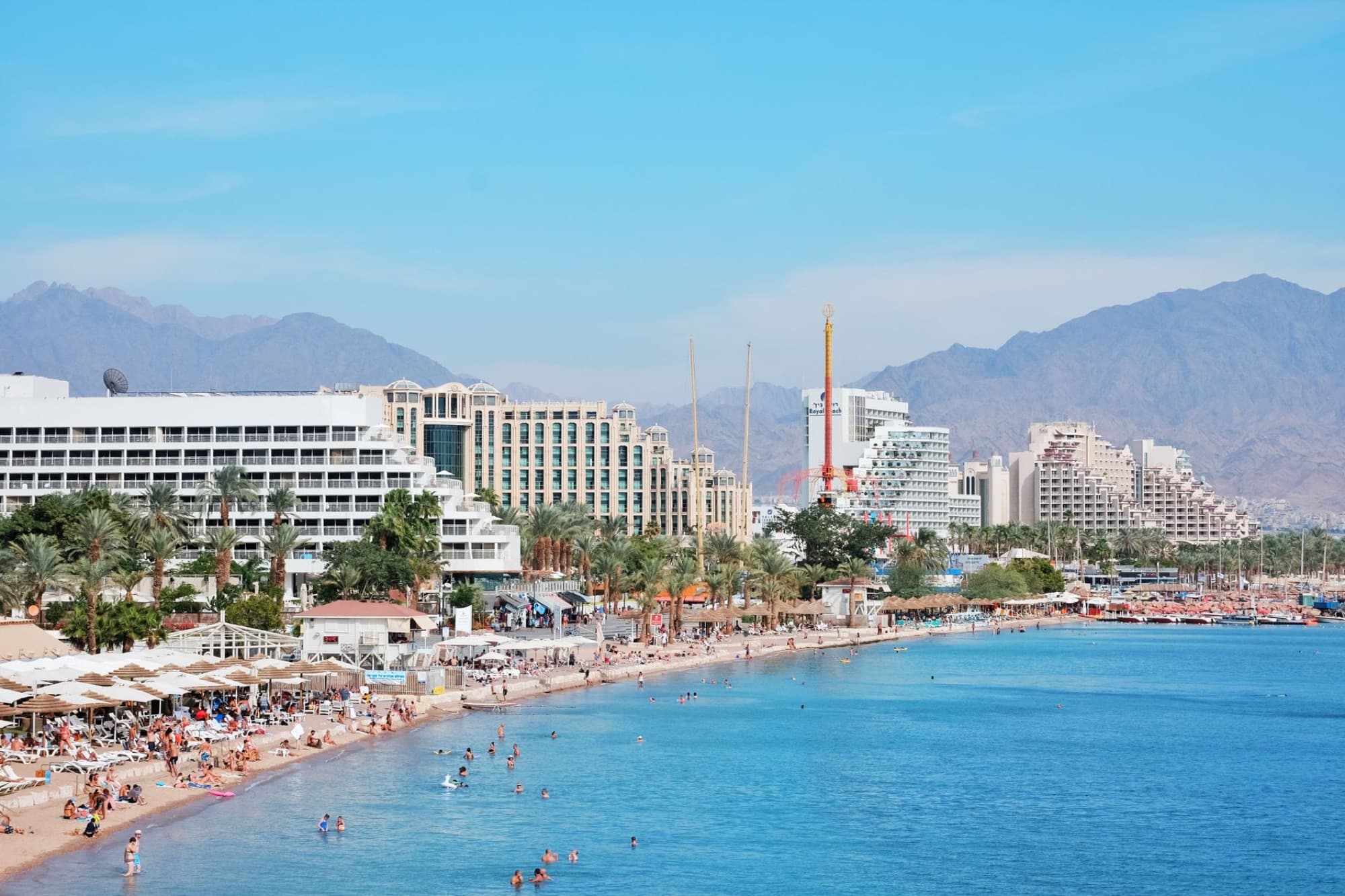 Scenic view of Eilat's coastal hotels and beach with distant mountains.