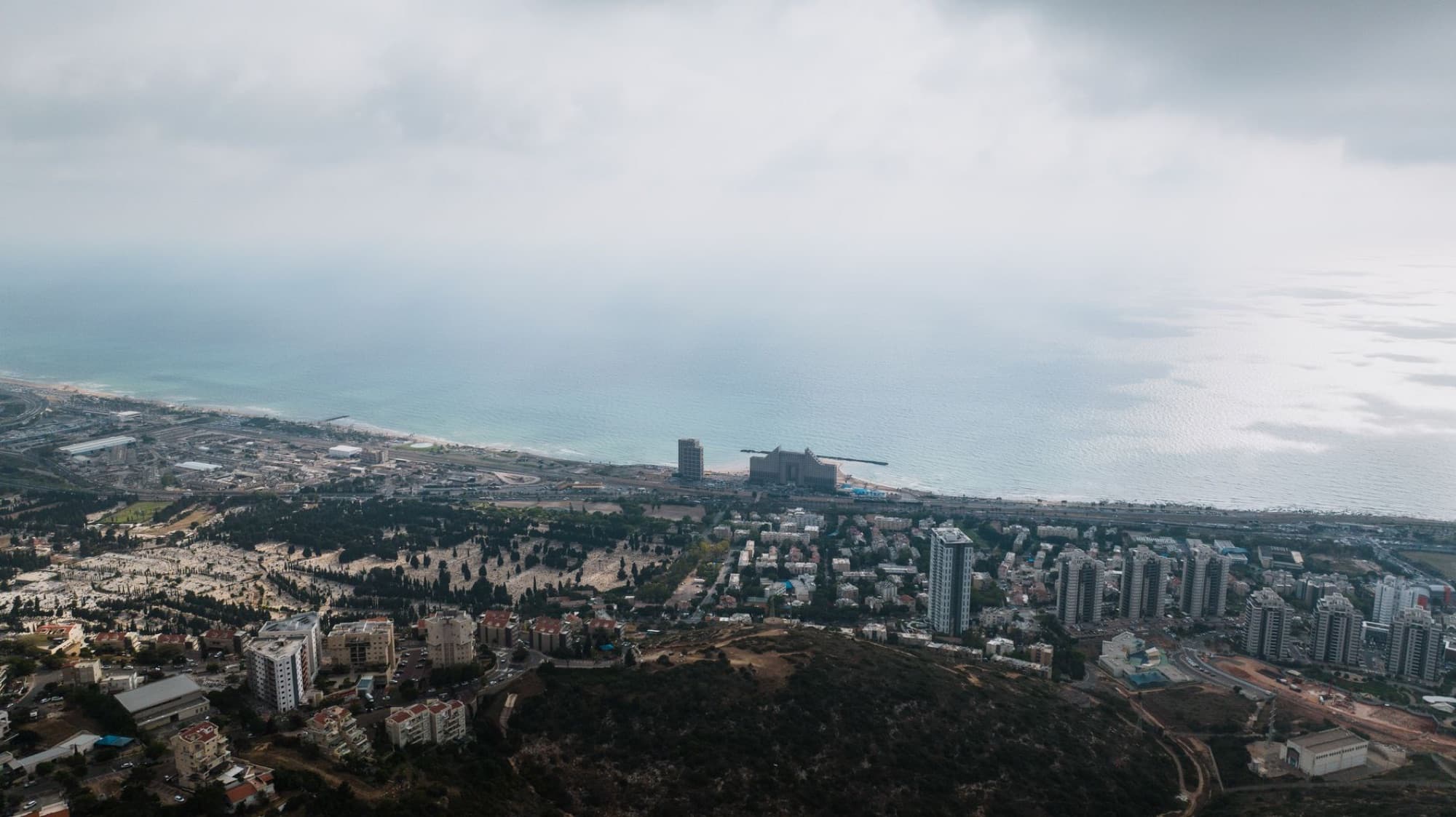 Explore the stunning aerial view of Haifa's coastline and urban landscape, captured on an overcast day.