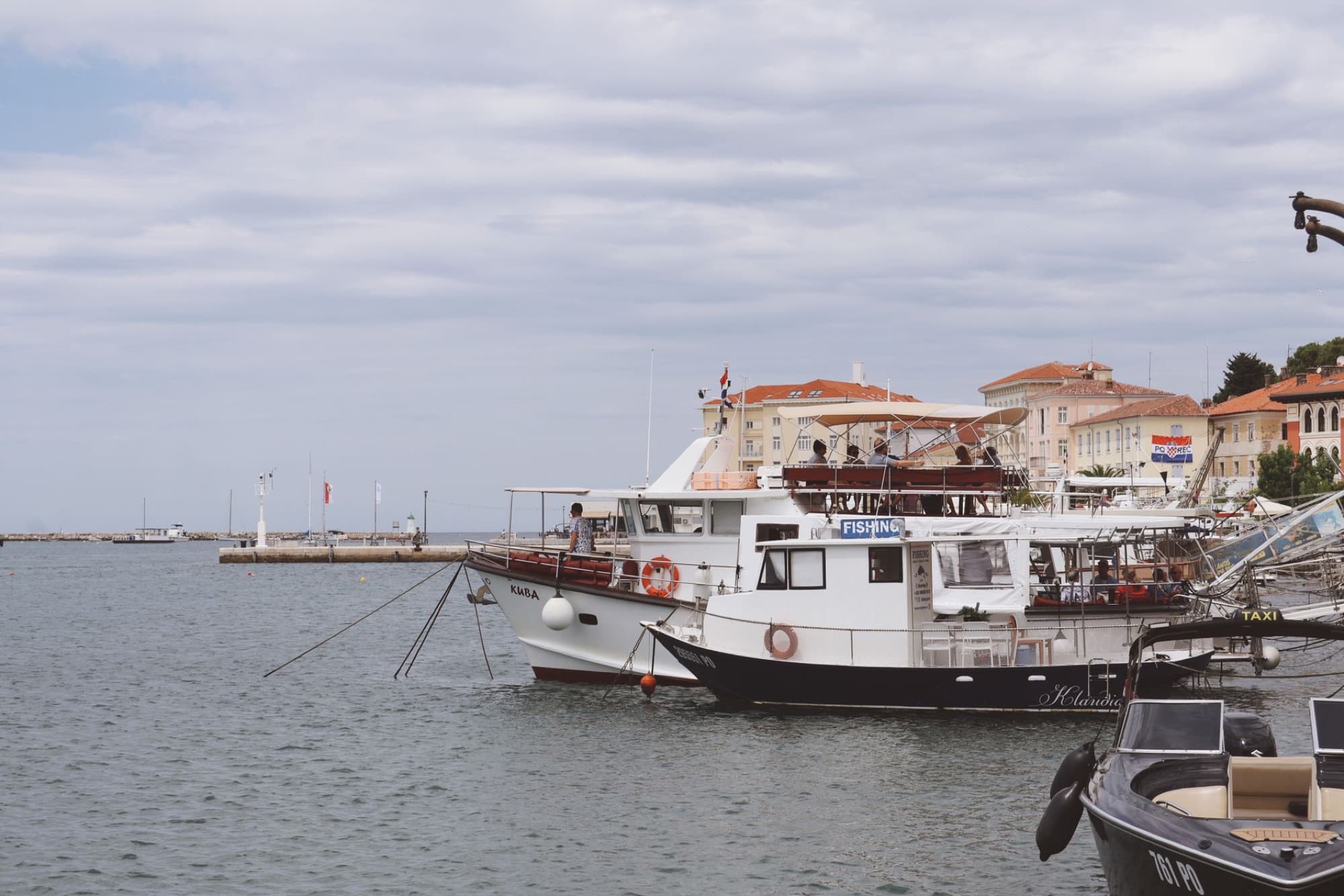 Boats docked at Poreč Harbor in Istria, Croatia on a cloudy day, showcasing a serene waterfront scene.