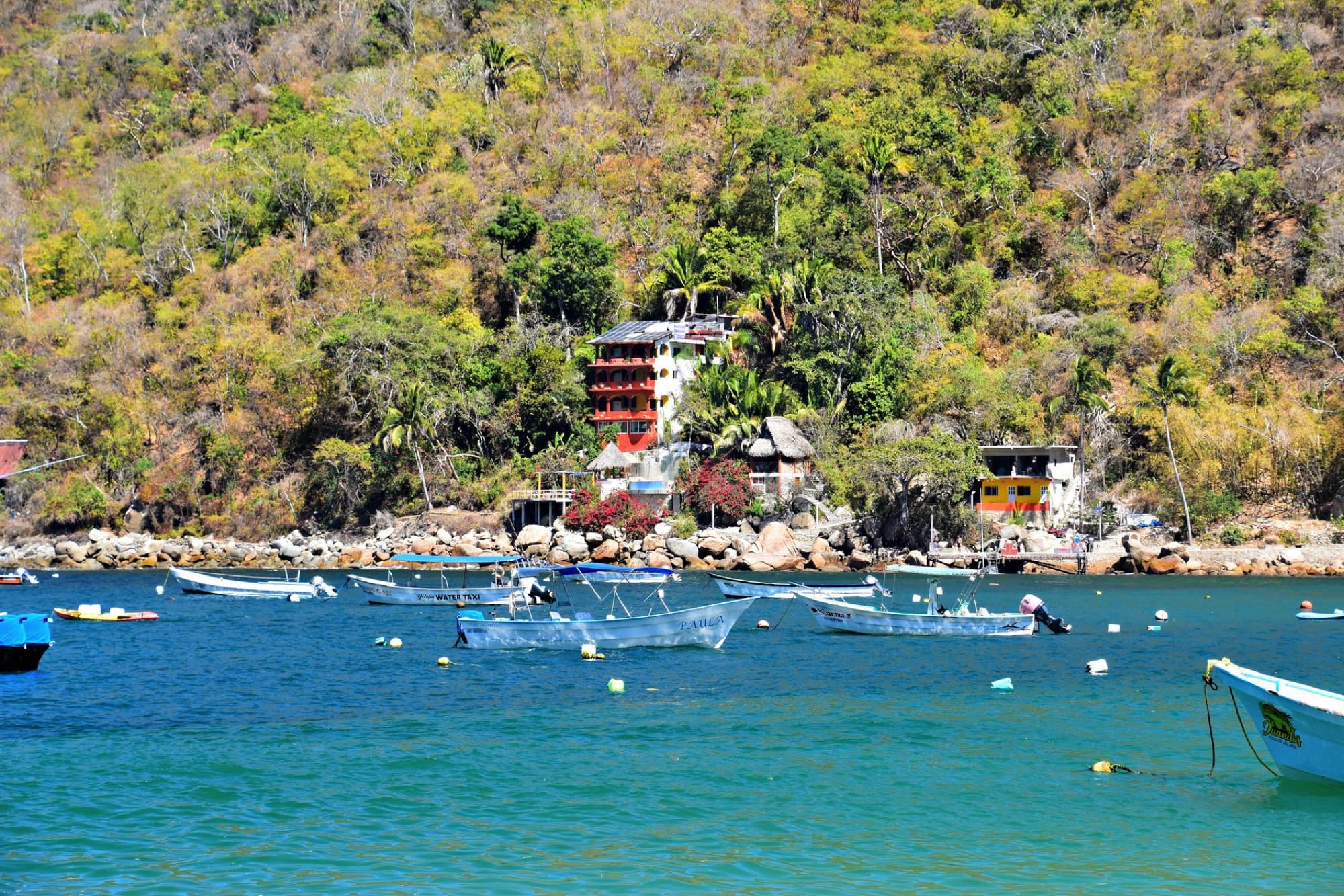 Scenic view of boats in Yelapa, Jalisco, Mexico, with vibrant green hillside backdrop.