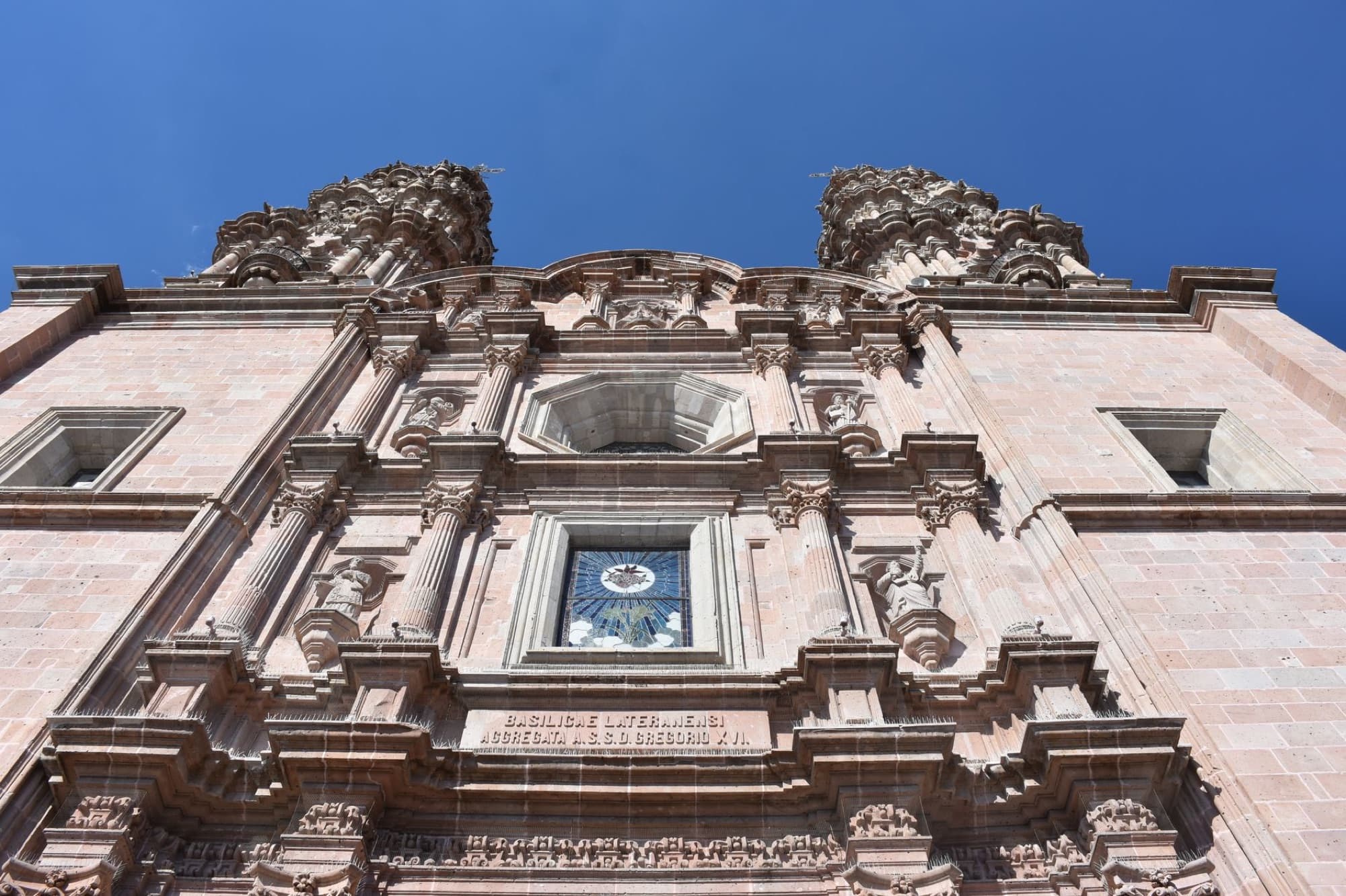 Detailed facade of the Basilica in San Juan de los Lagos, Jalisco, under a vibrant blue sky.
