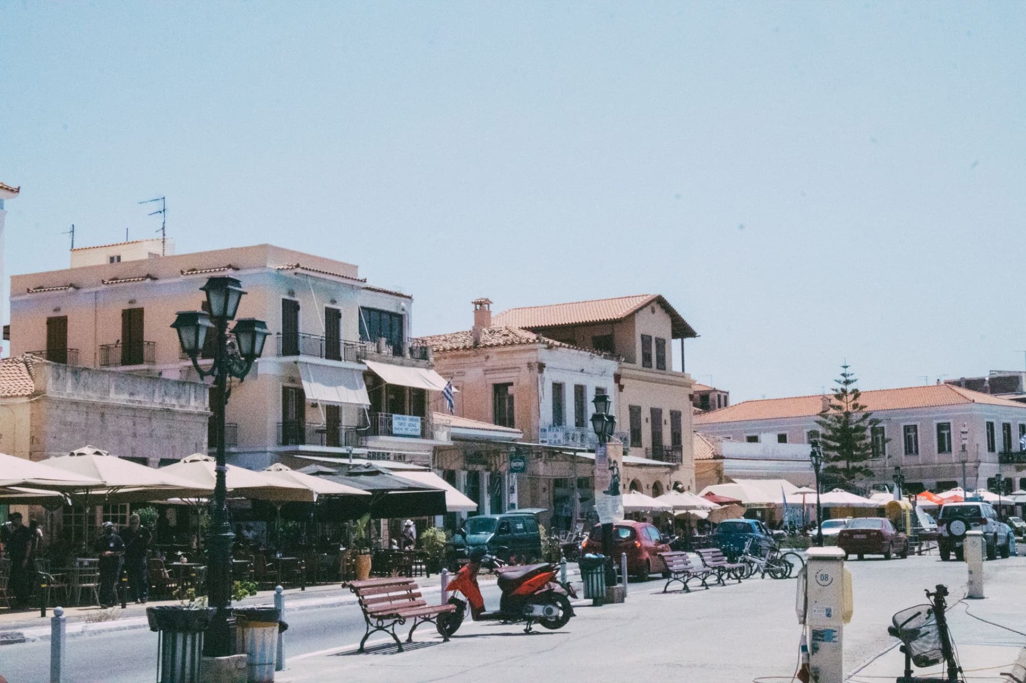 Vibrant street scene in a Mediterranean town with outdoor cafes and historic buildings.