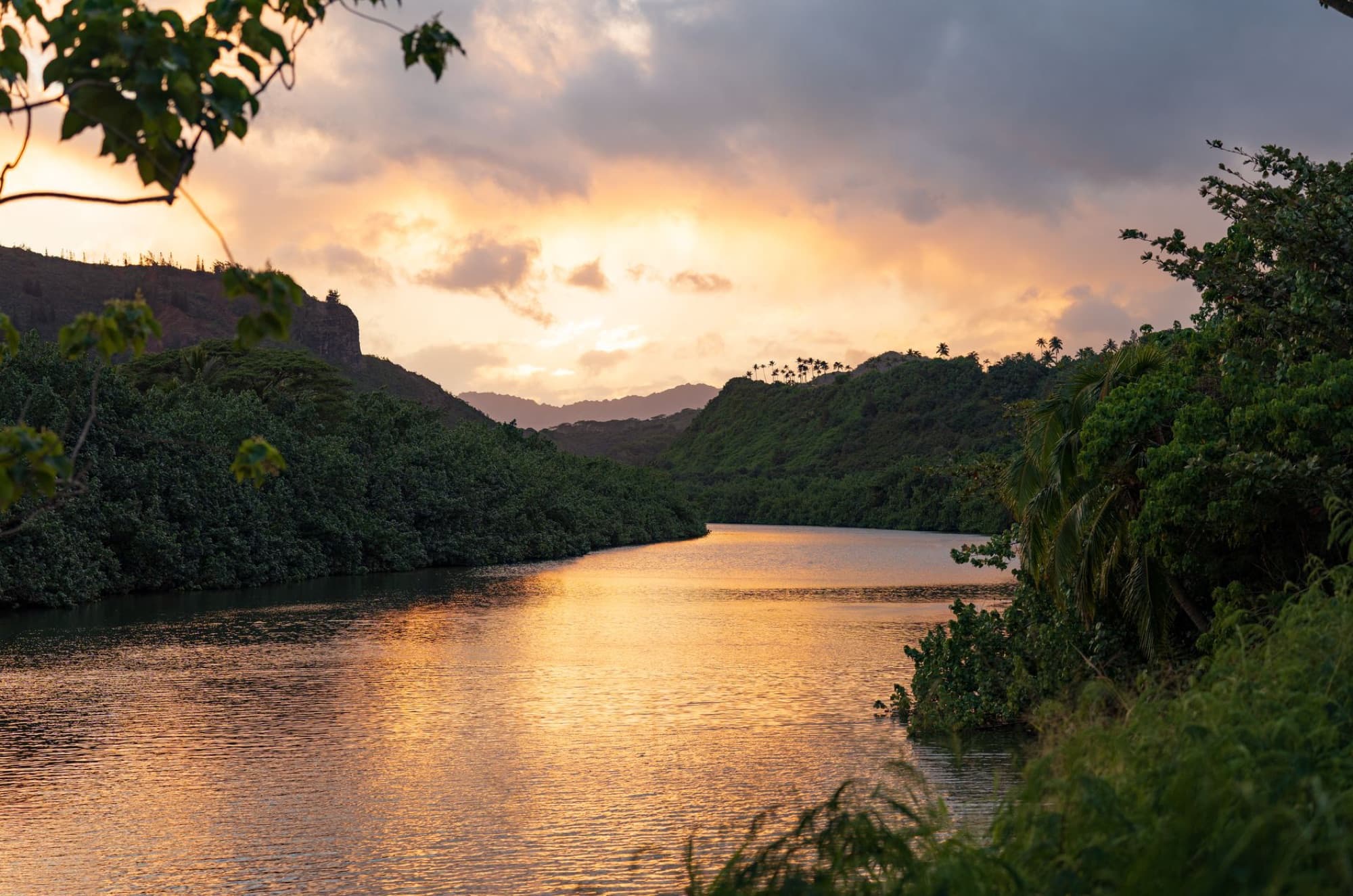 Beautiful sunset over Wailua River in Kauai, showcasing lush greenery and vibrant skies.