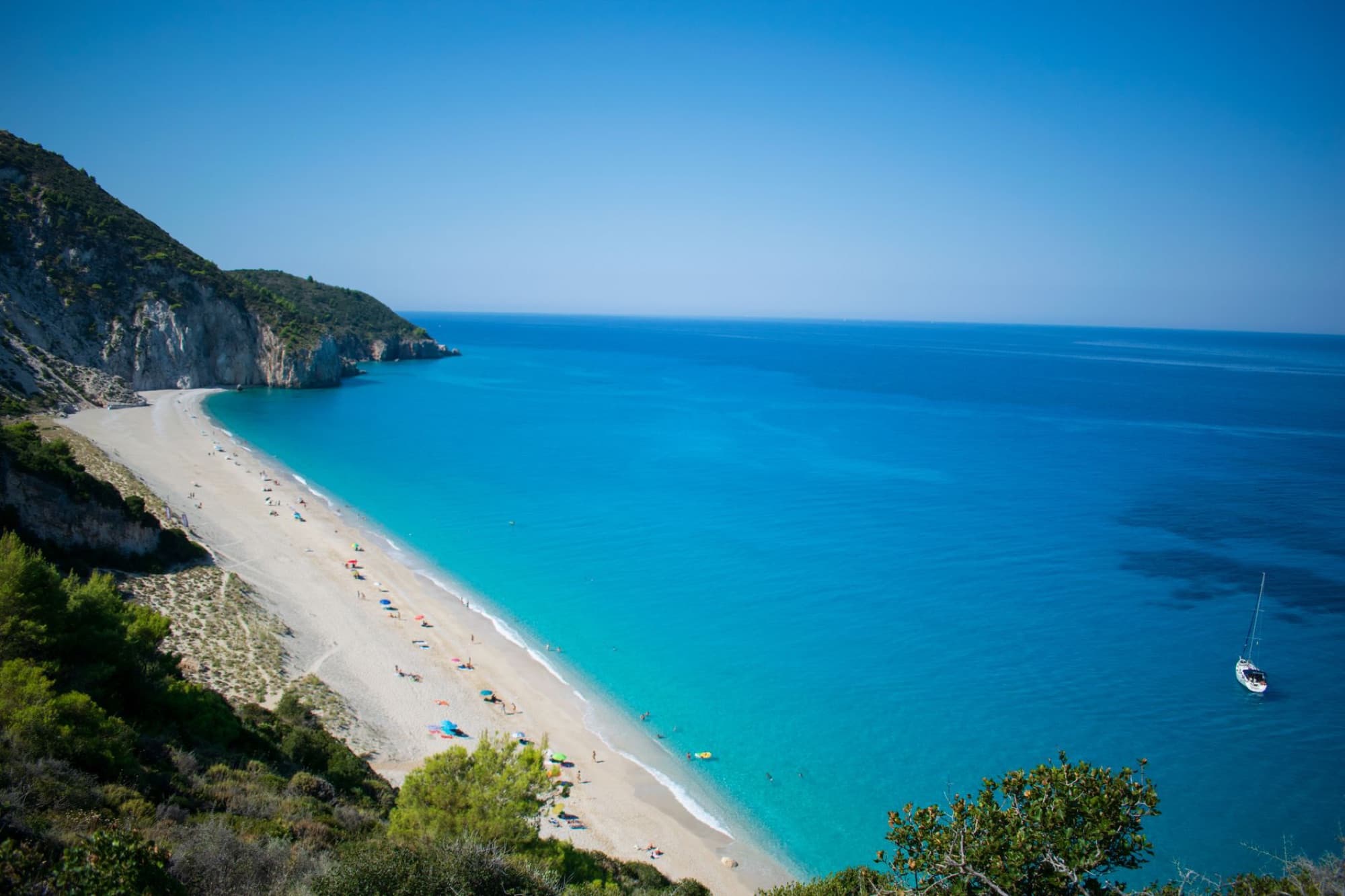 Stunning aerial view of the turquoise waters and sandy beach of Lefkada, Greece, with lush cliffs and a serene atmosphere.