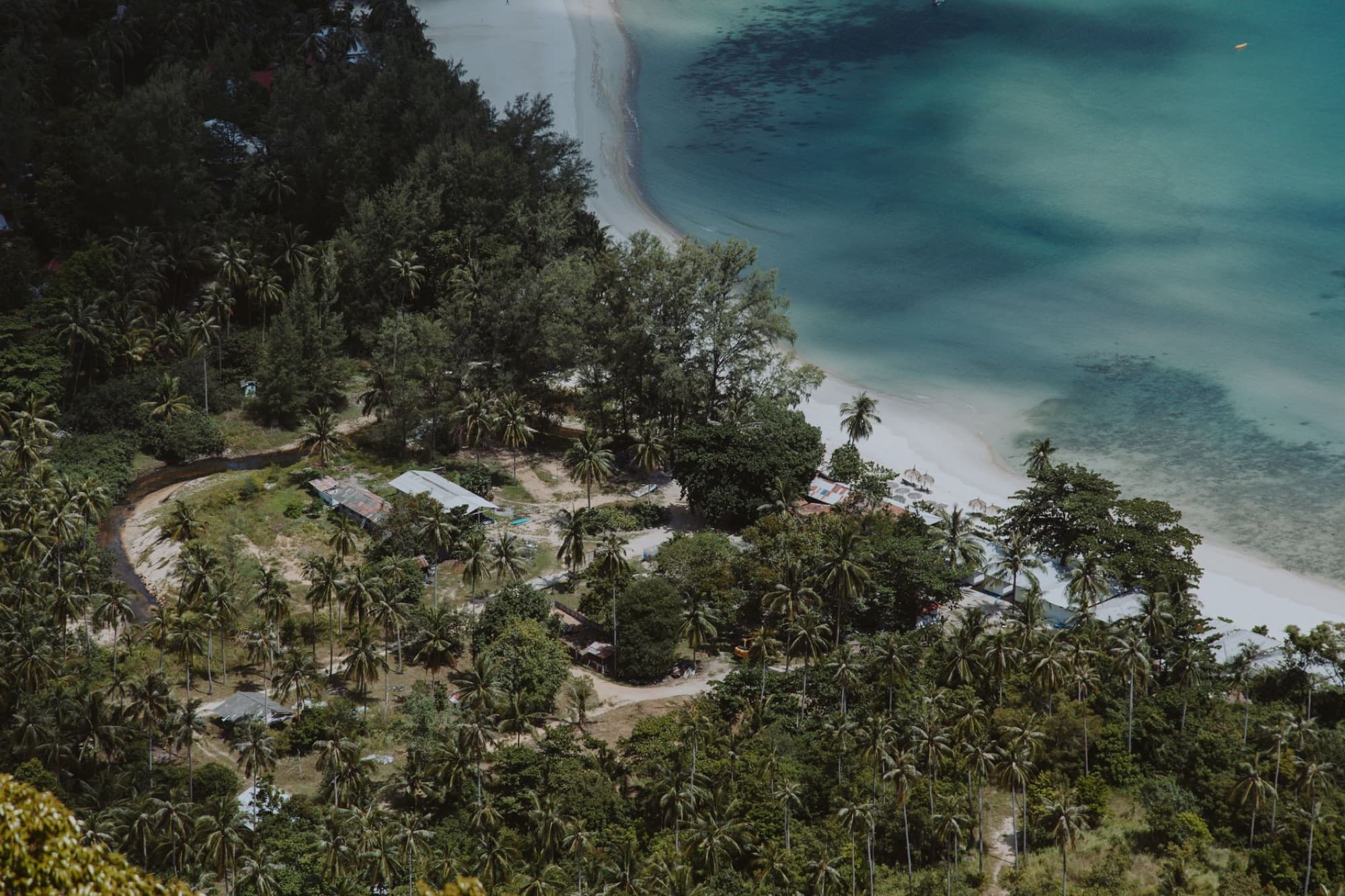 Aerial view of a tropical coastline with lush greenery and clear blue waters, perfect for travel and nature enthusiasts.