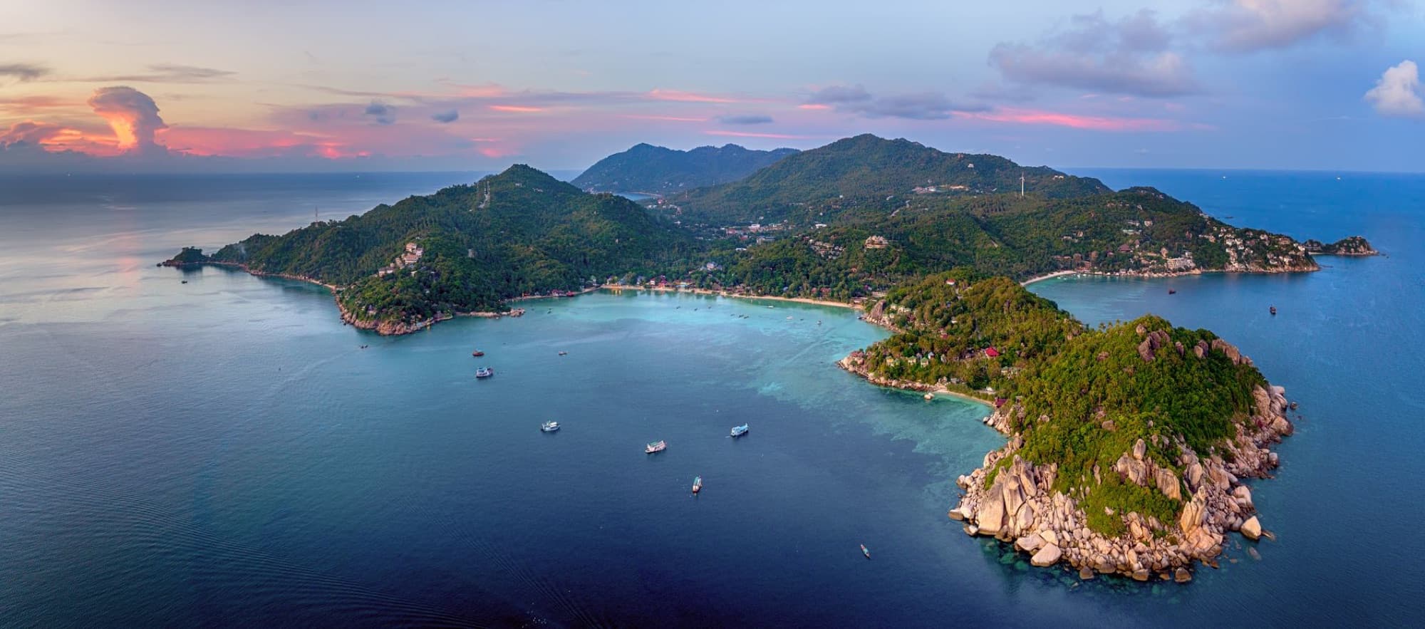 A breathtaking aerial view of Koh Tao Island, Thailand at sunset, surrounded by azure waters.