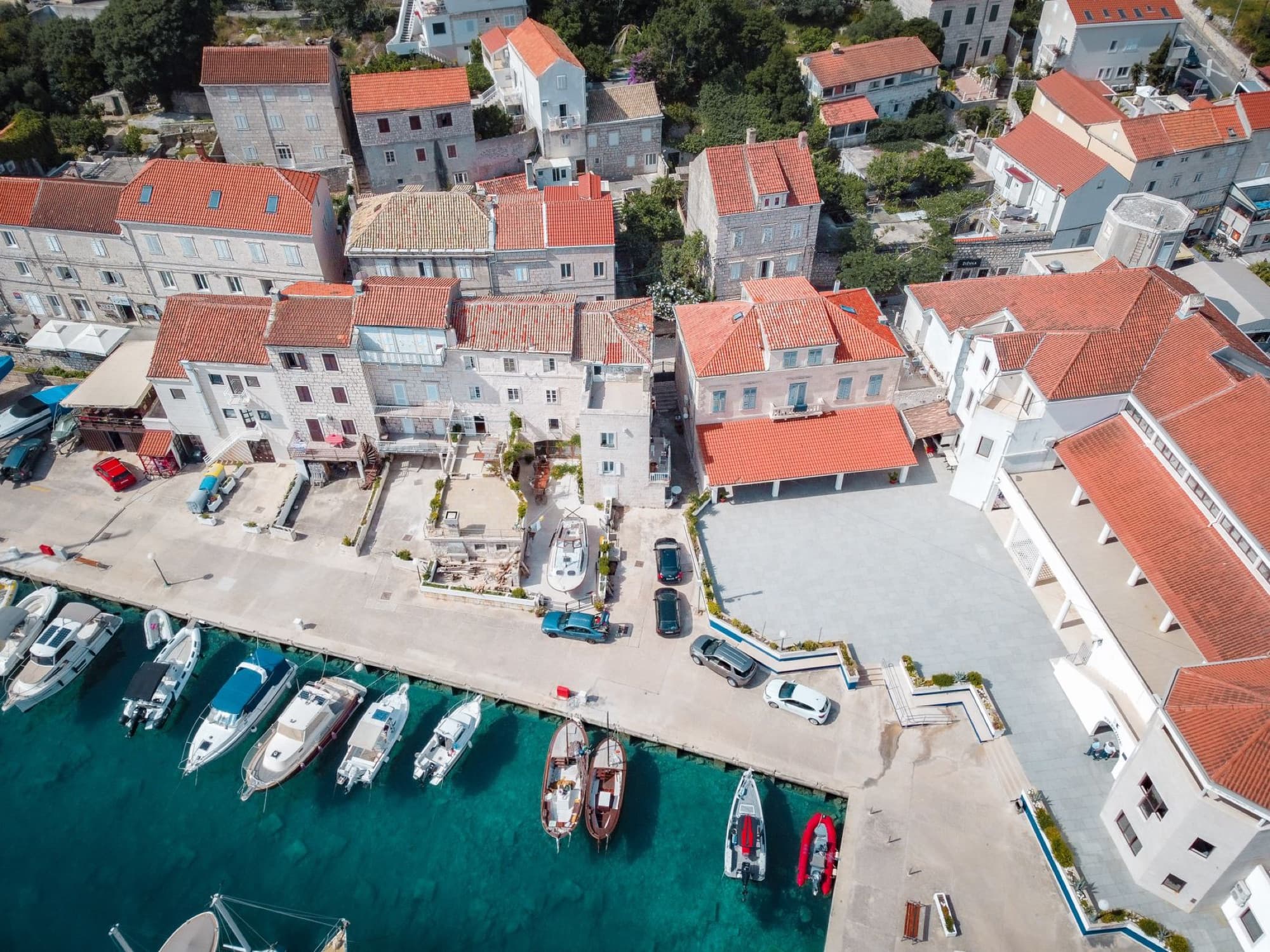 A picturesque aerial view showing the marina and red-roofed buildings of Korčula's waterfront in summer.