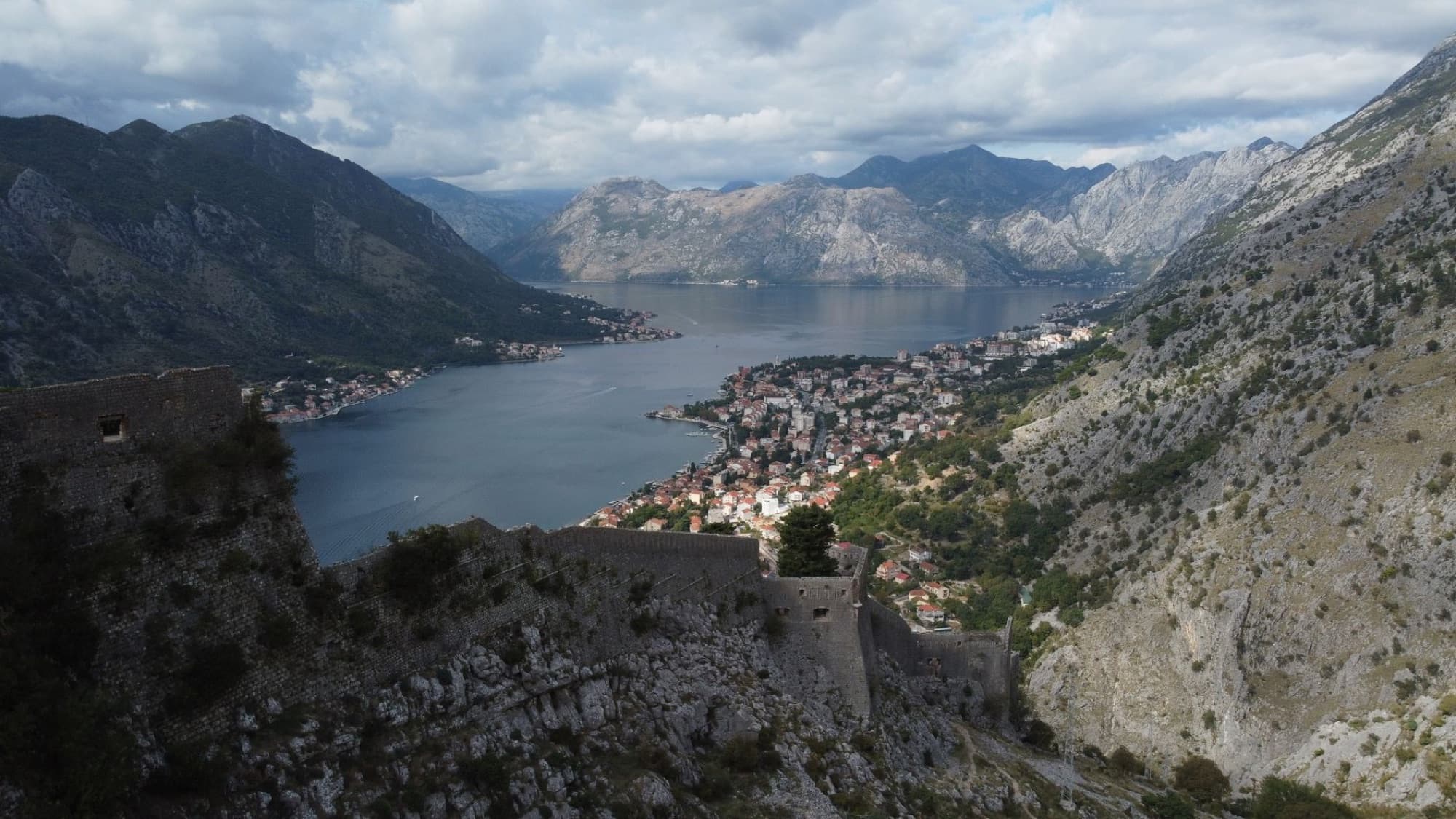 Scenic aerial view of Kotor Bay, Montenegro with surrounding mountains and historic castle ruins.