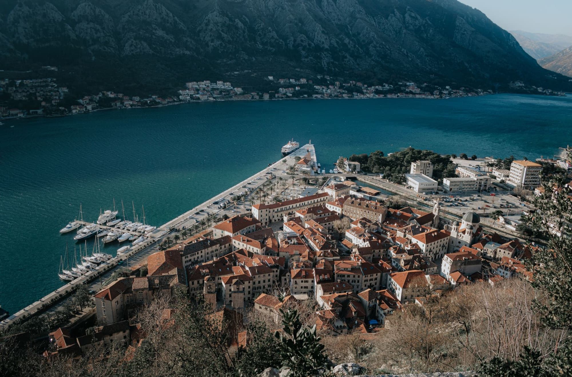 Breathtaking aerial view of Kotor's coastal town, marina, and mountains in Montenegro.
