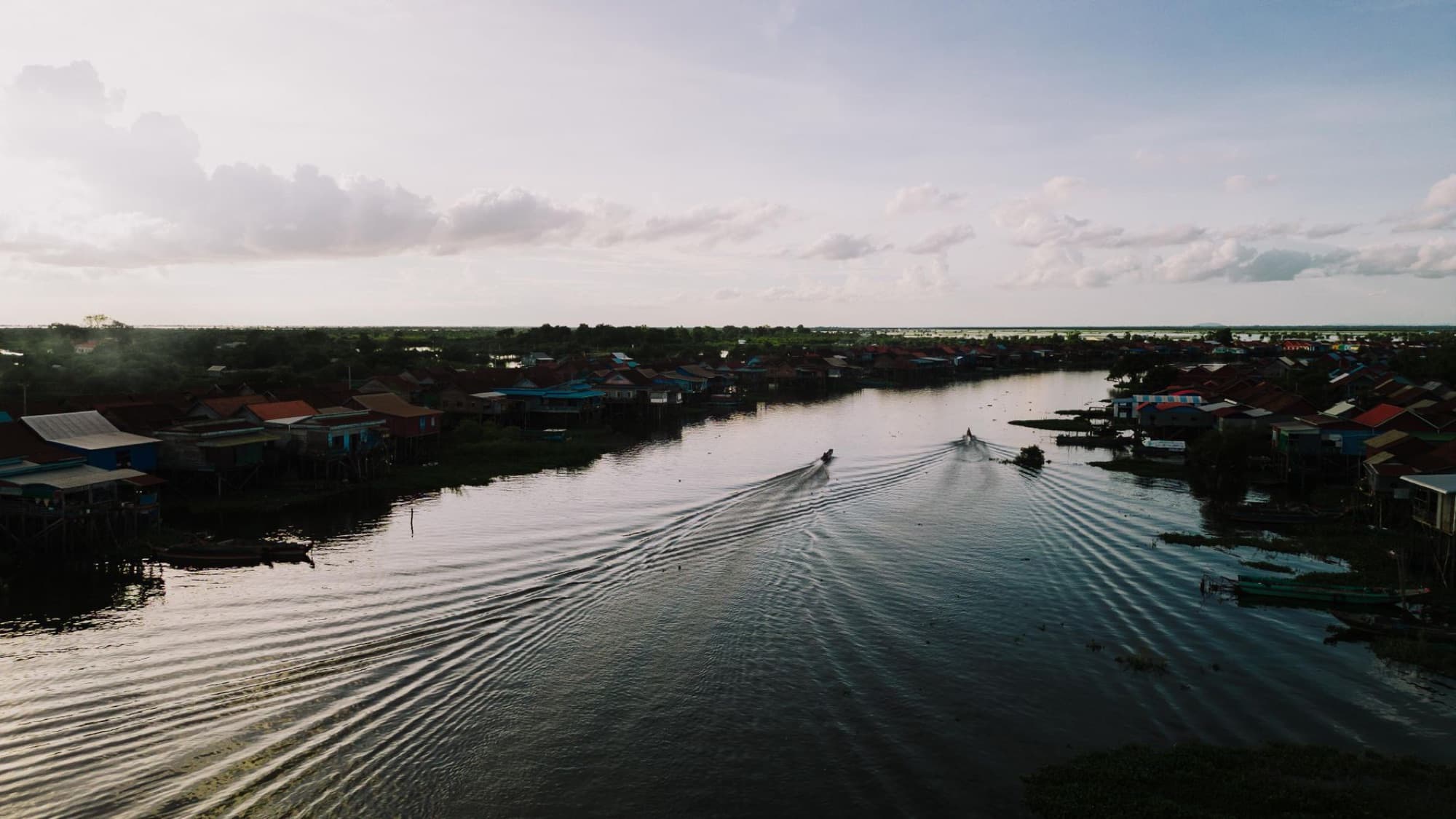 Aerial view of boats navigating the river in Kampong Khleang, Cambodia at sunset.