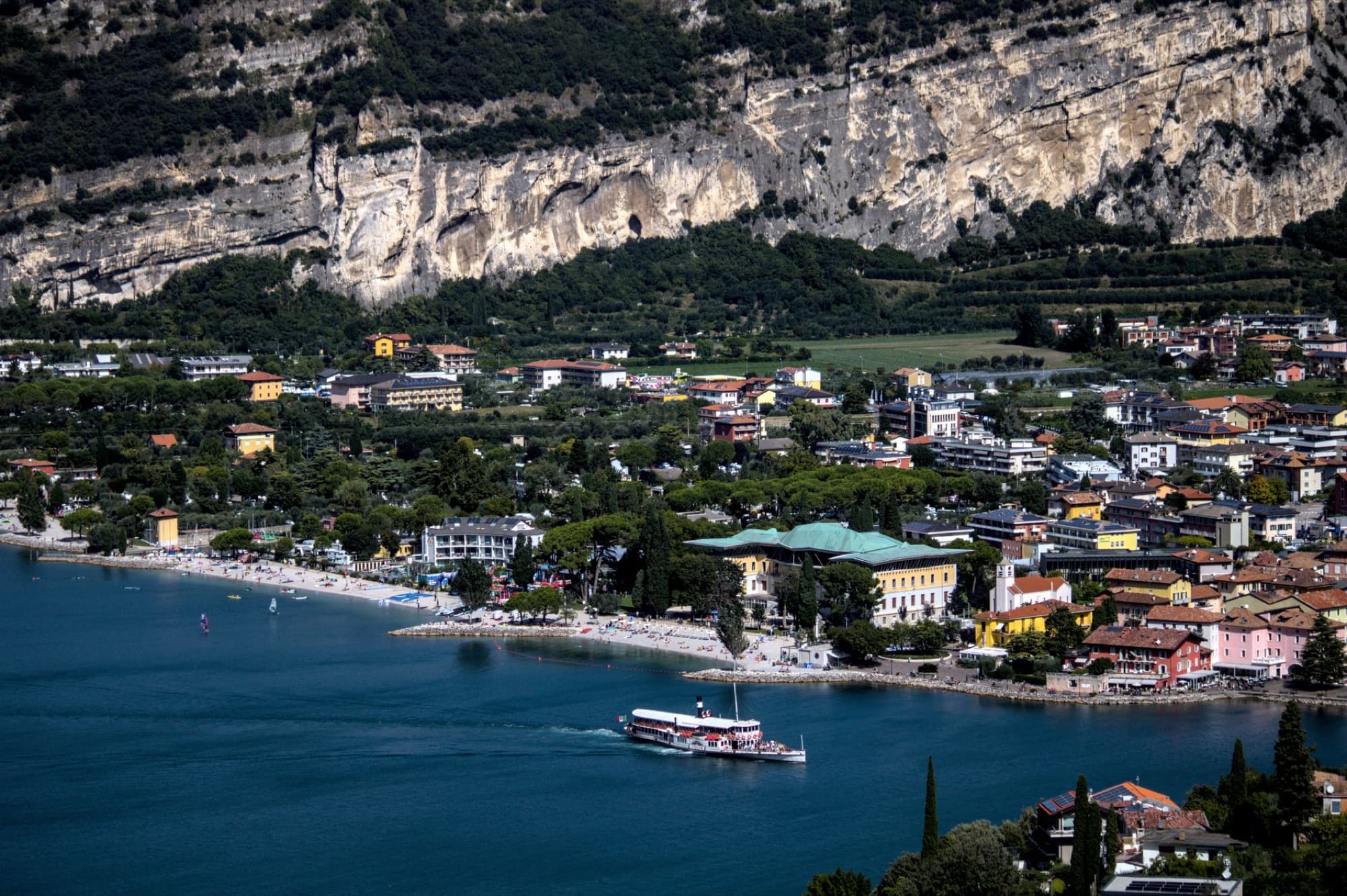 Aerial view of Riva del Garda and Lake Garda surrounded by mountains on a sunny day.