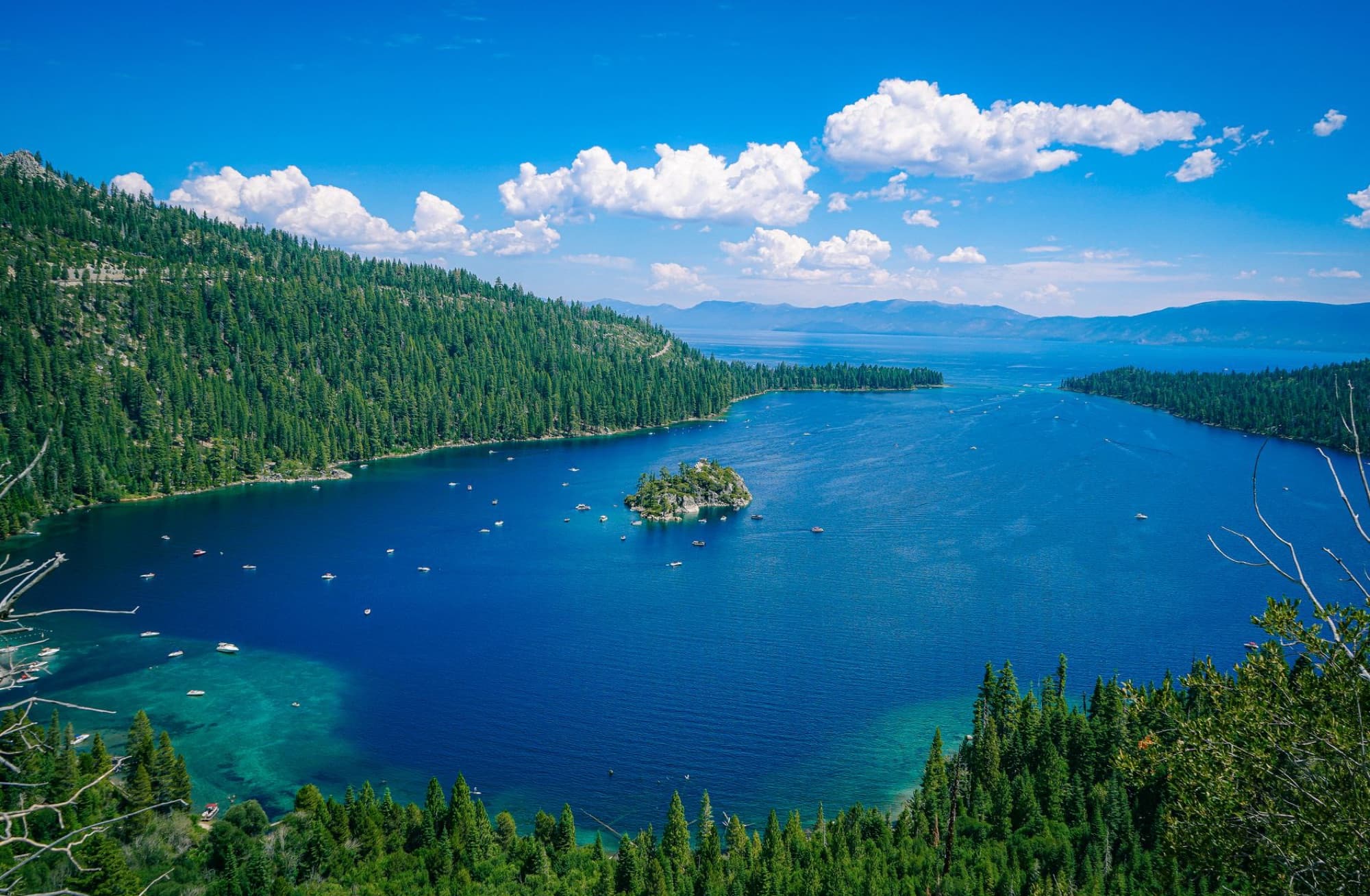A breathtaking aerial view of Lake Tahoe's emerald bay and Fannette Island under a clear blue sky.