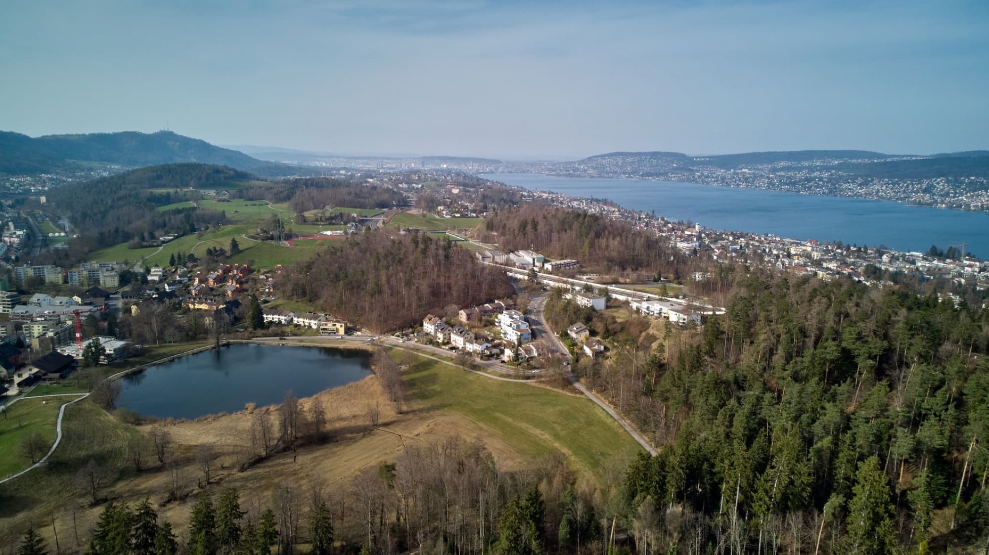 Scenic aerial view of Thalwil, Switzerland, overlooking Lake Zurich with lush greenery and hills.