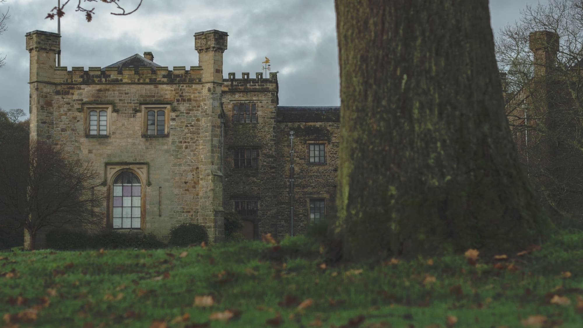 Towneley Hall in Lancashire, surrounded by lush greenery and a moody sky.