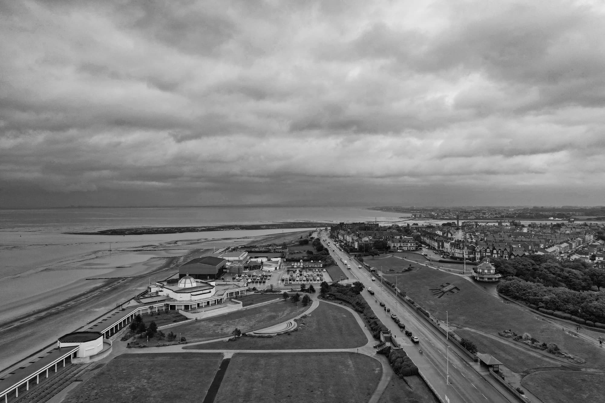 A tranquil aerial shot capturing Morecambe Bay and promenade under cloudy skies, showcasing the beauty of the coastal town.