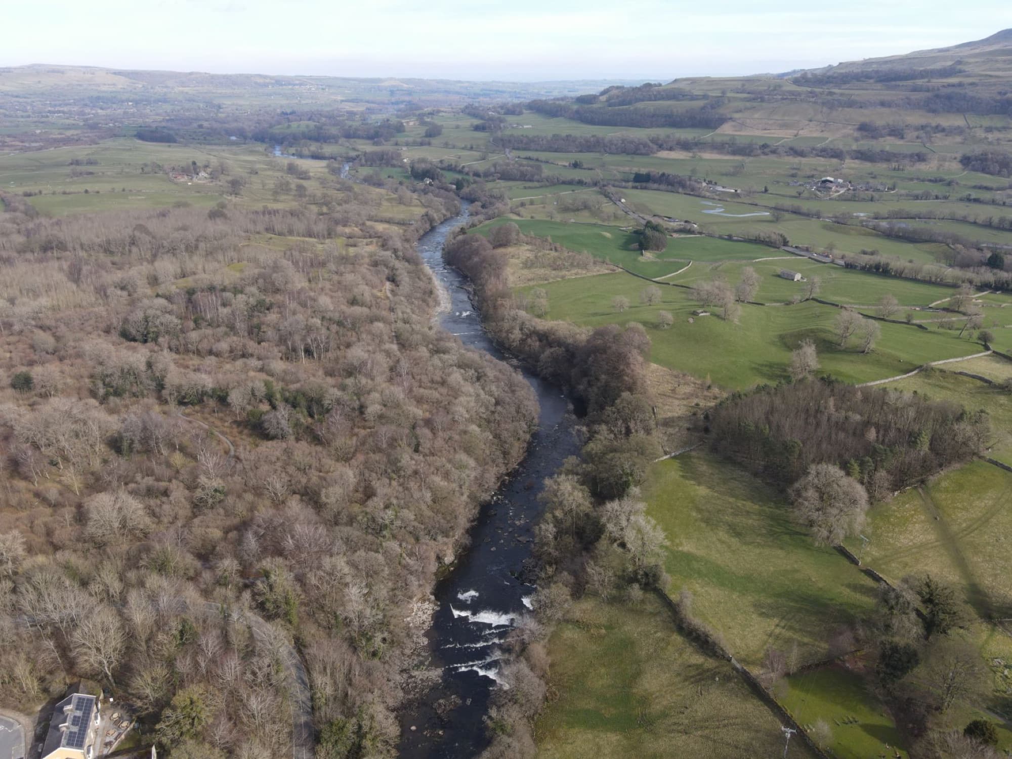 A beautiful aerial view showcasing a river winding through lush countryside fields and forests.