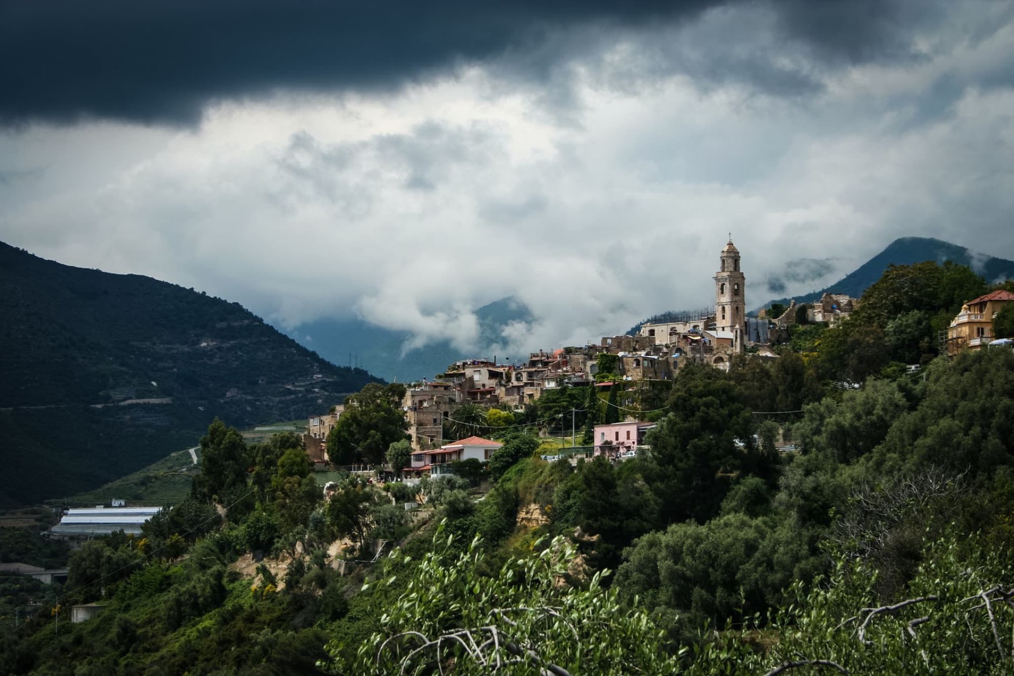 A stunning view of a hilltop village in Lazio, Italy under a moody sky, surrounded by lush nature.