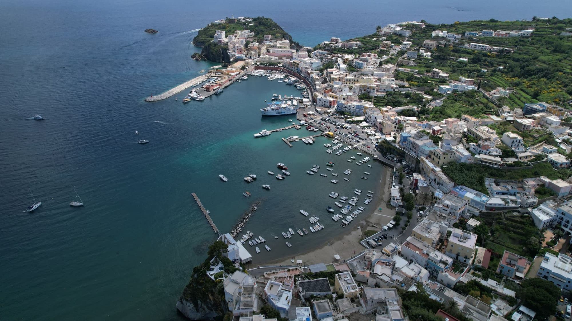 A stunning aerial view of Ponza Island harbor with boats and coastal town in summer.