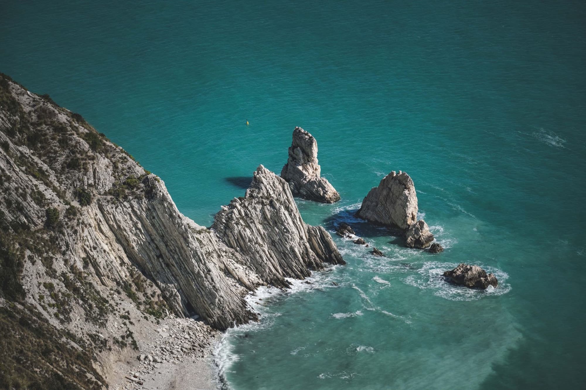 Breathtaking aerial shot of Due Sorelle Beach's rocky cliffs and turquoise sea in Italy.