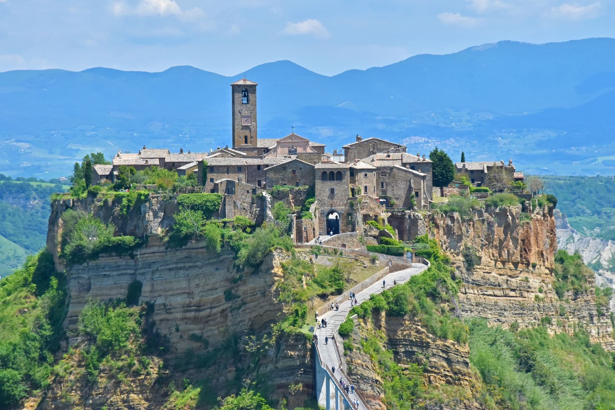 Scenic view of Civita di Bagnoregio perched on a cliff with mountain backdrop.