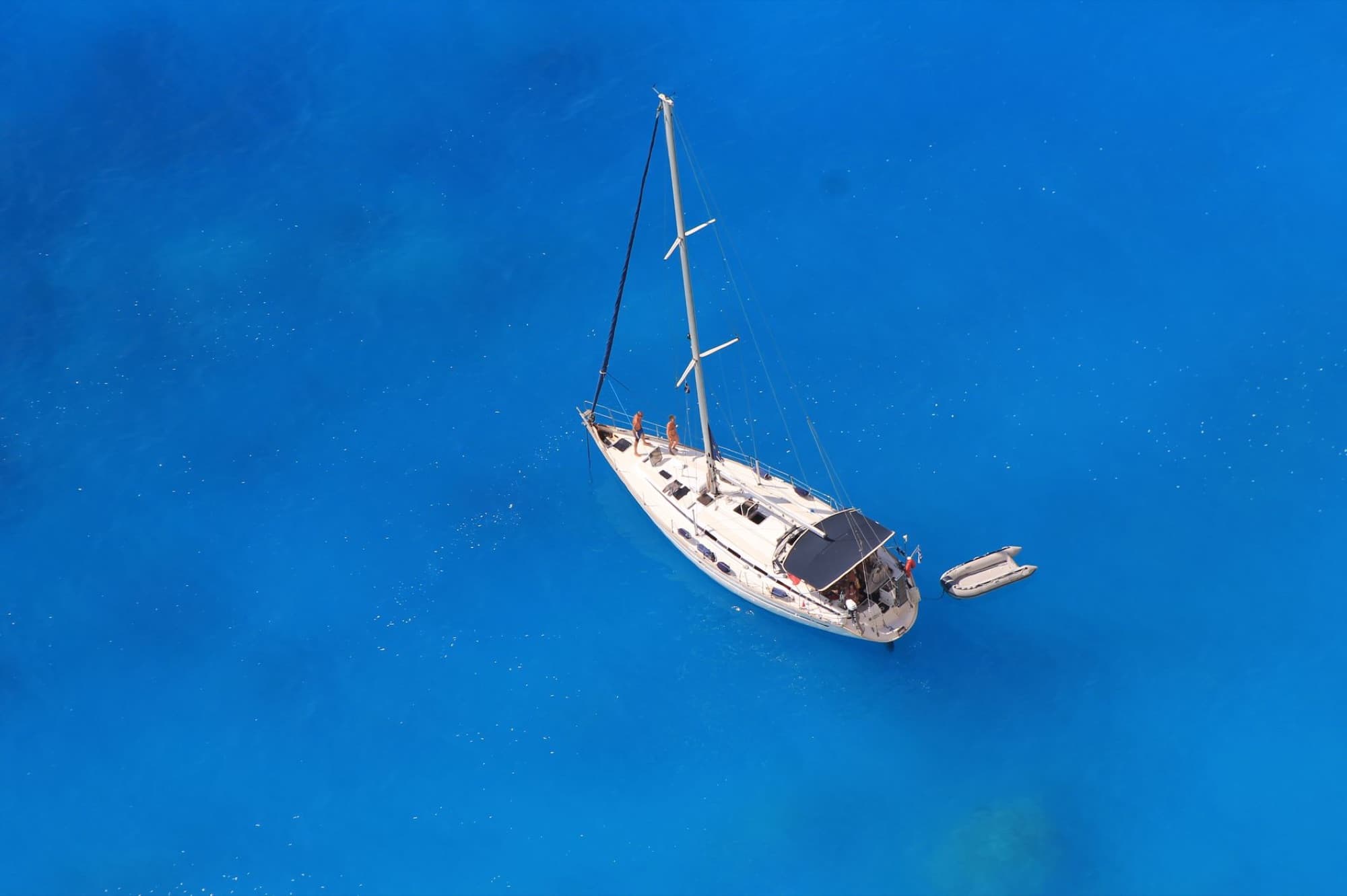 Aerial shot of a sailboat floating on stunning blue waters in Lefkada, Greece. Perfect for adventure seekers.