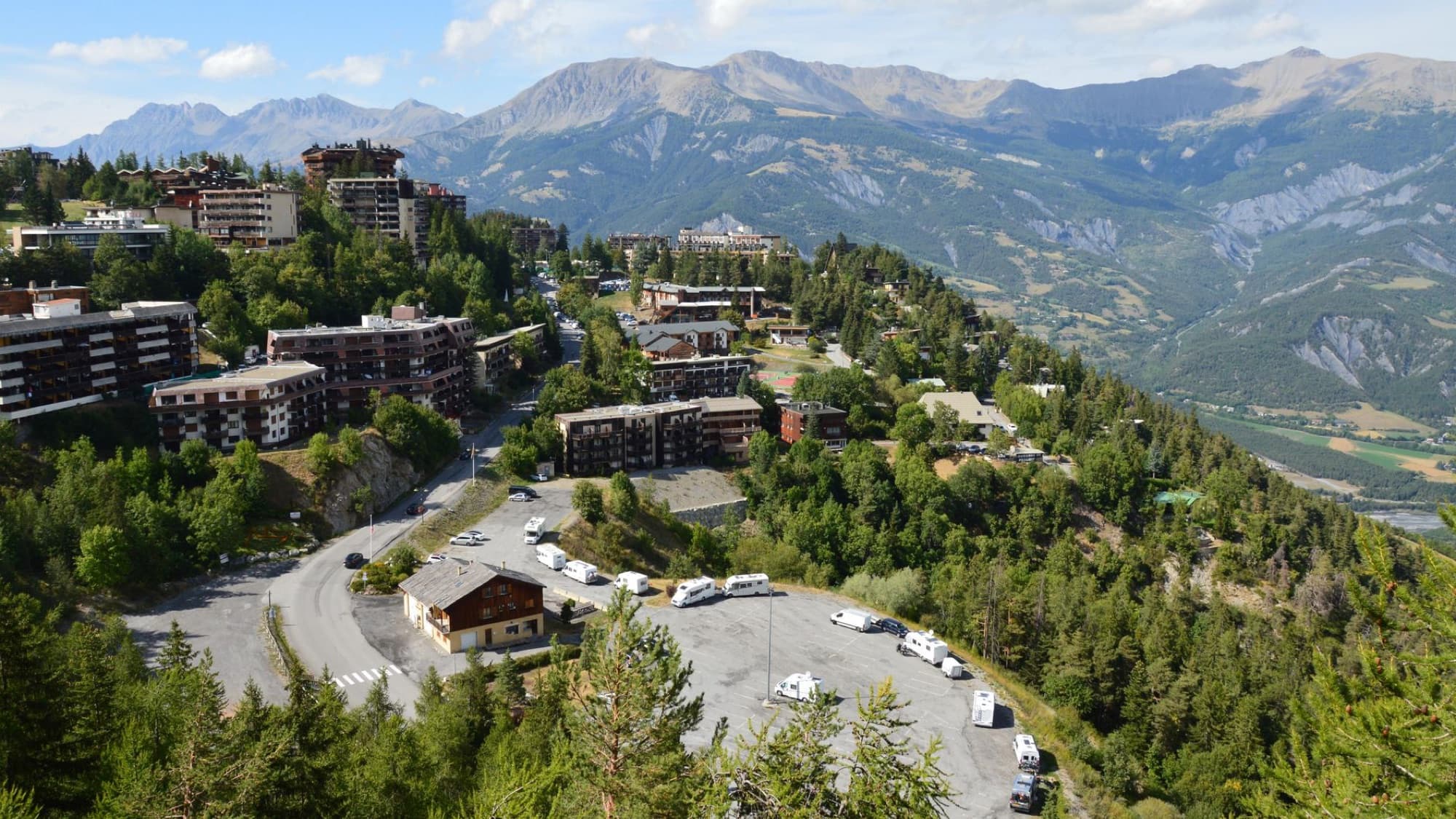Aerial view of a mountainous town surrounded by lush forests and rugged mountains.