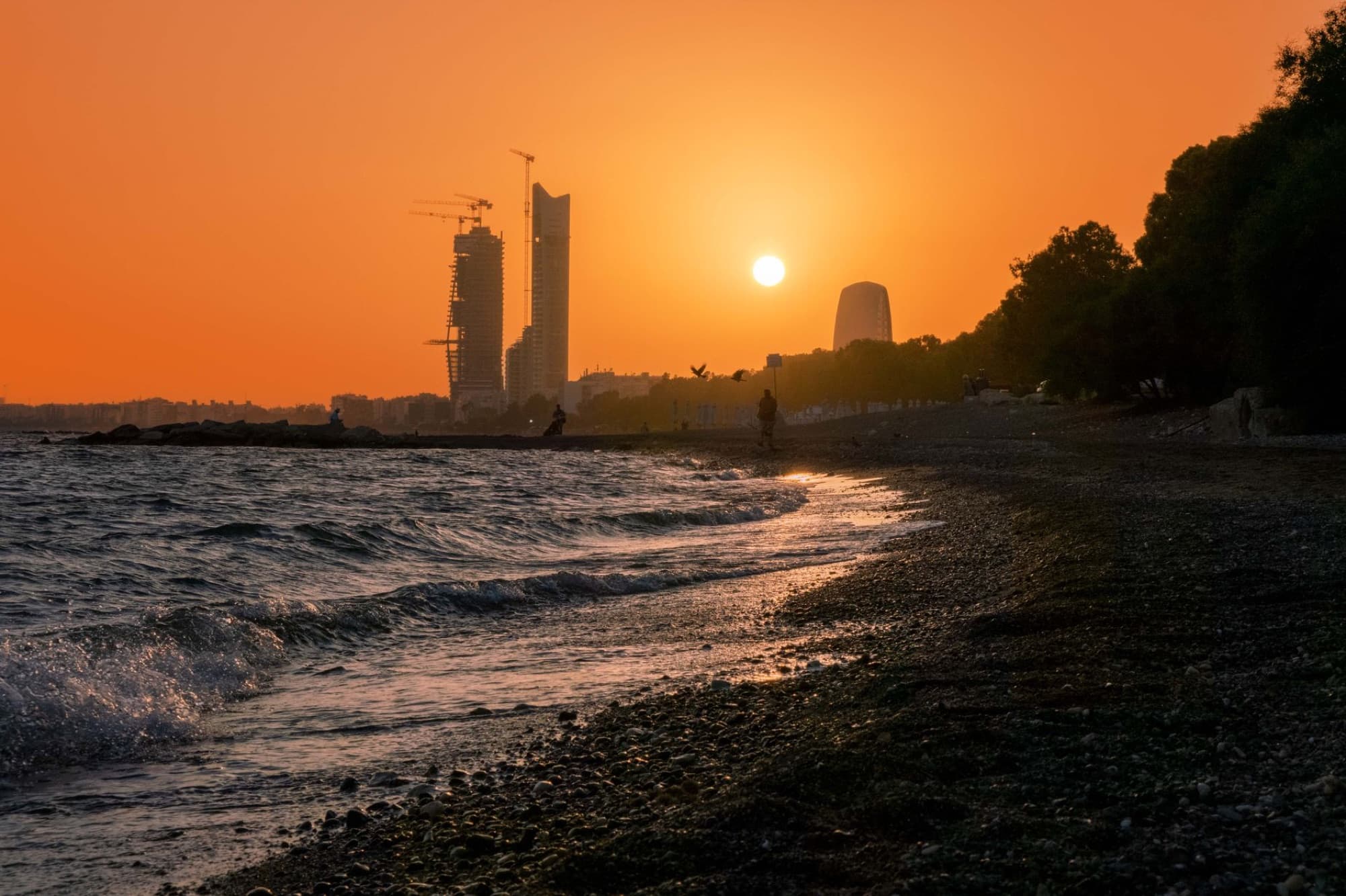 Breathtaking sunset view over Limassol beach with urban skyline and orange sky.