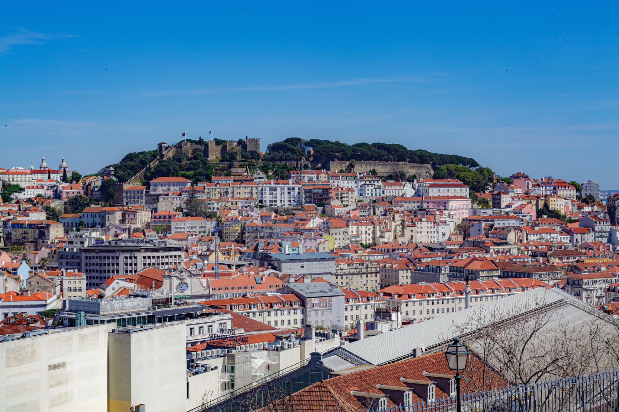 Stunning aerial view of Lisbon's rooftops and historic Castle Hill on a clear day.