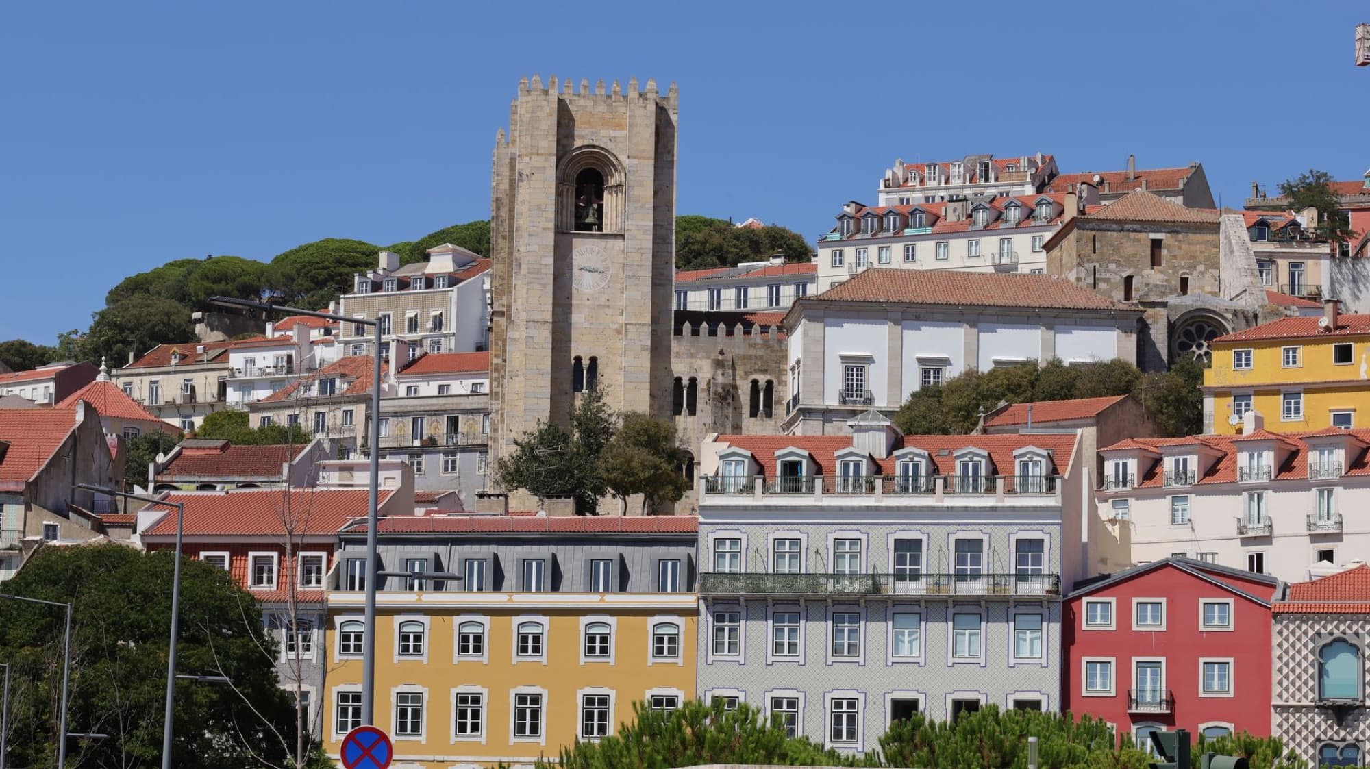 Scenic view of Lisbon Cathedral with vibrant rooftops under a clear summer sky.