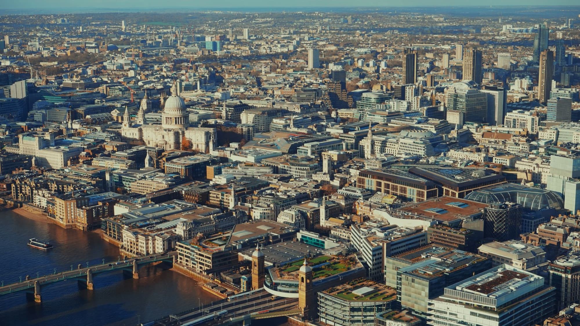 A breathtaking aerial view of London's urban skyline showcasing St. Paul's Cathedral and the River Thames.
