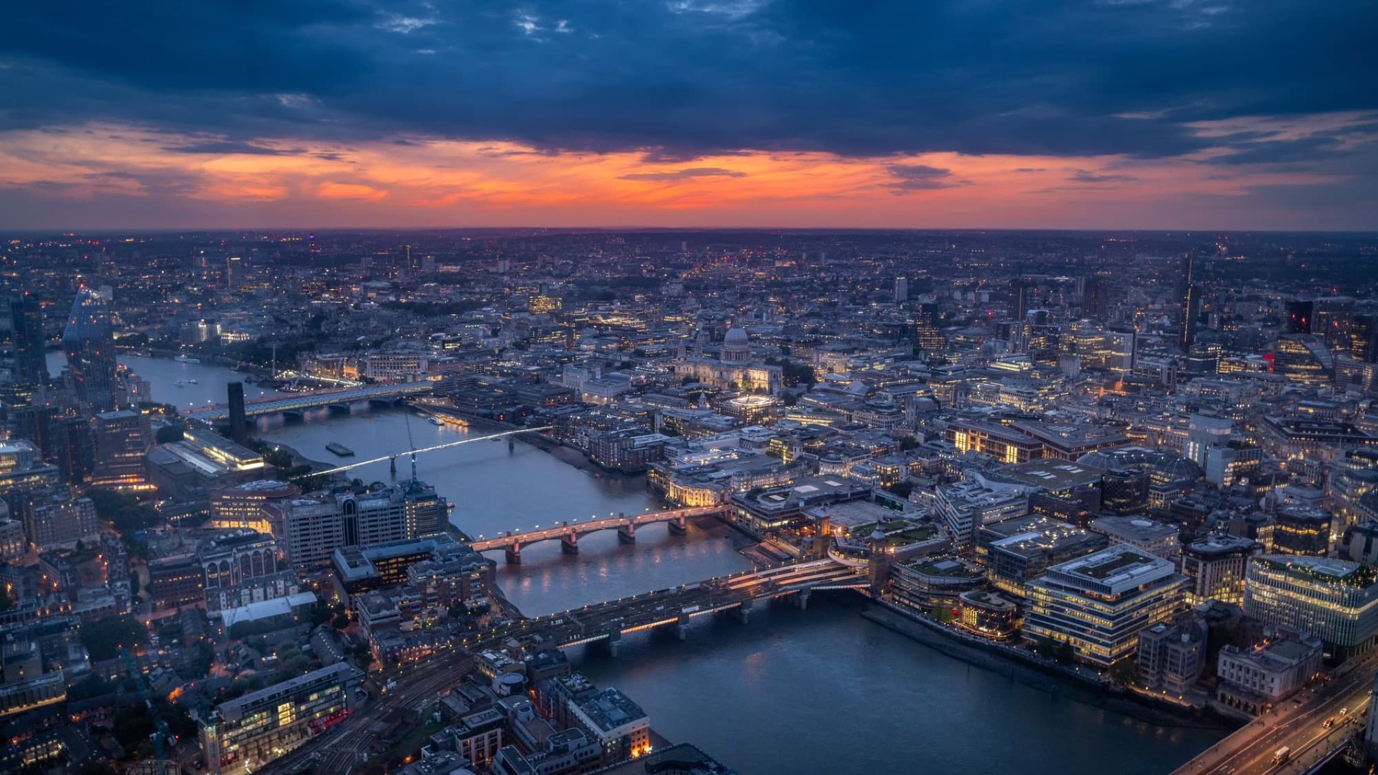 A breathtaking aerial view of London's cityscape with the Thames River at sunset, showcasing the urban landscape.