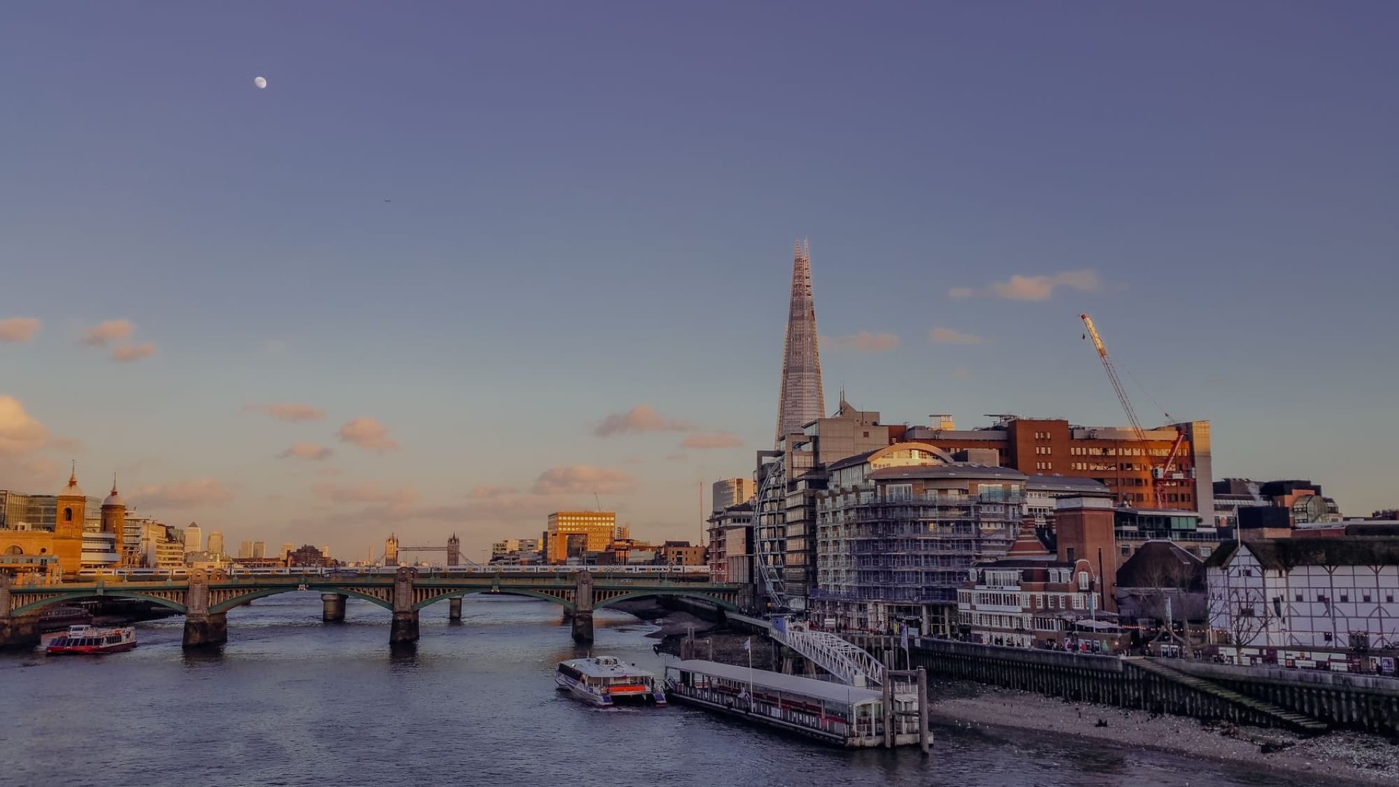 Scenic view of London skyline with The Shard and Thames River at sunset, offering a serene cityscape.