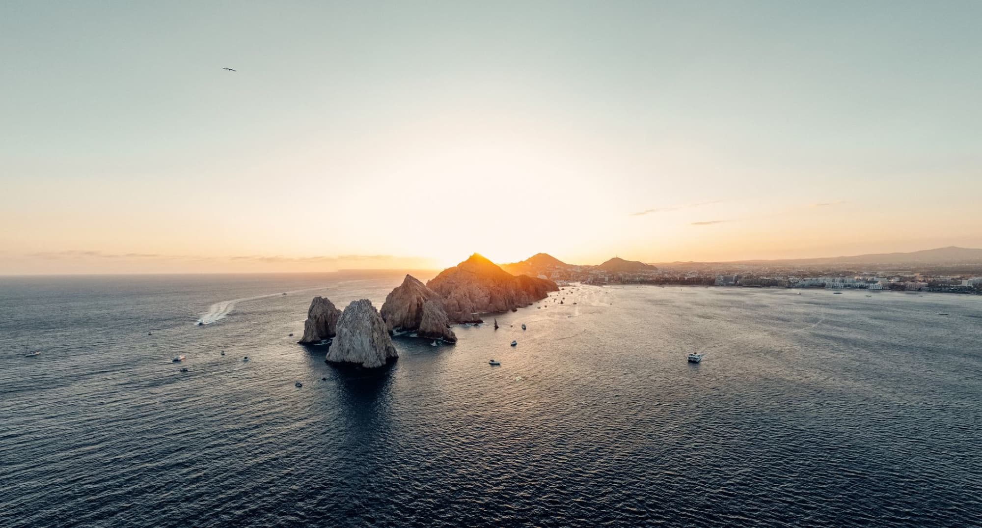 A stunning aerial view of the rocky coastline at Cabo San Lucas during sunset.