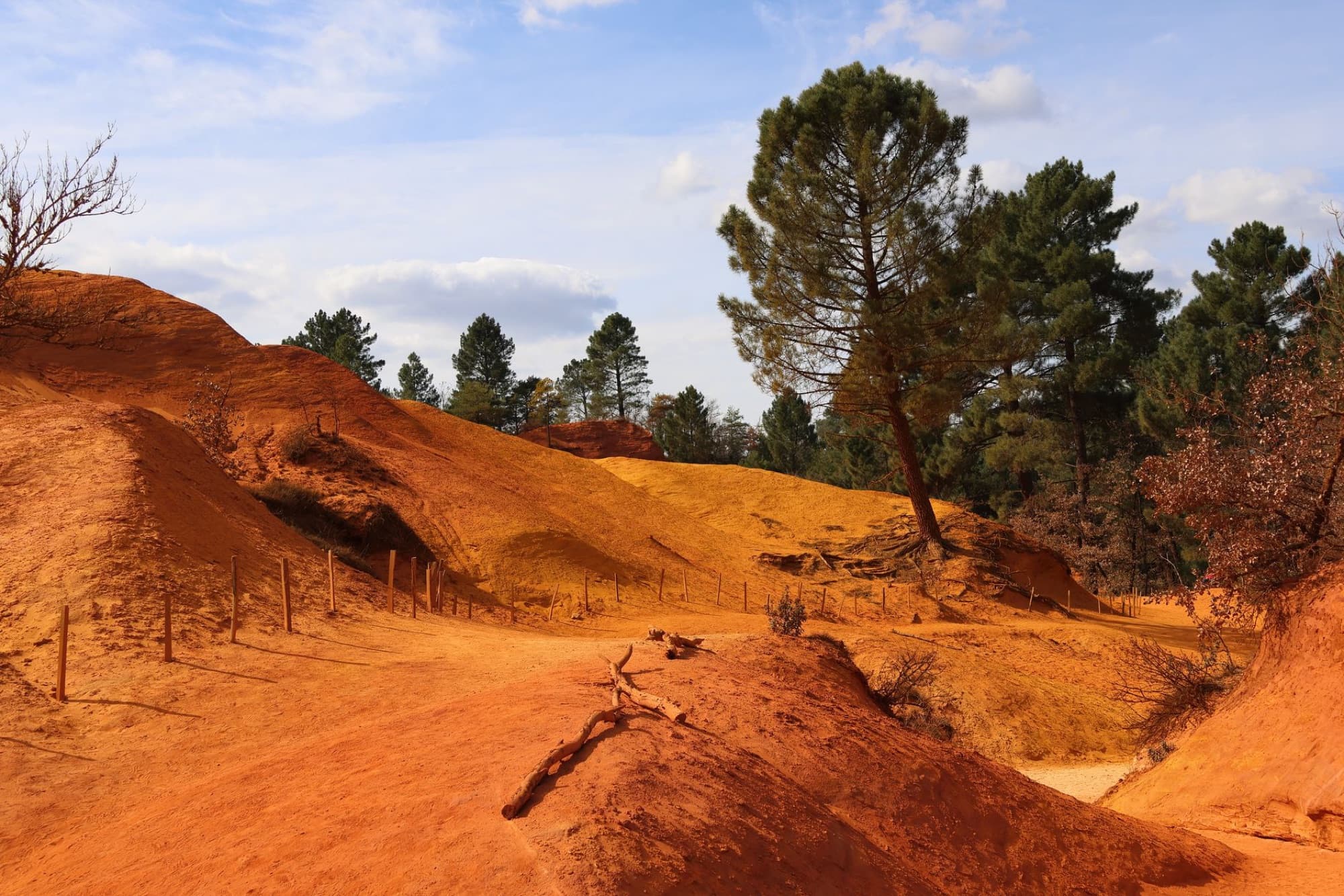 Explore the vibrant orange ochre hills and scenic trails in the captivating landscape of Rustrel, France.