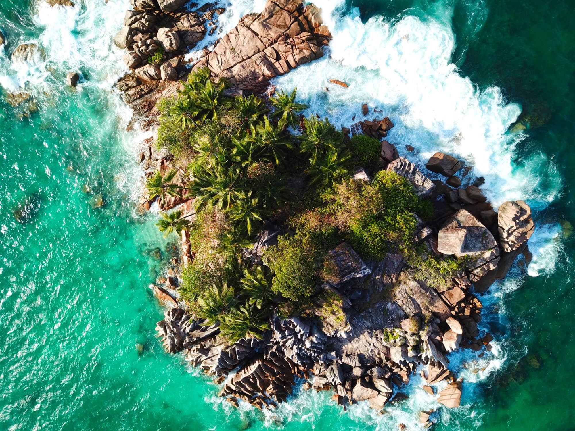 Stunning aerial shot capturing a rocky tropical island surrounded by turquoise waters in Seychelles.