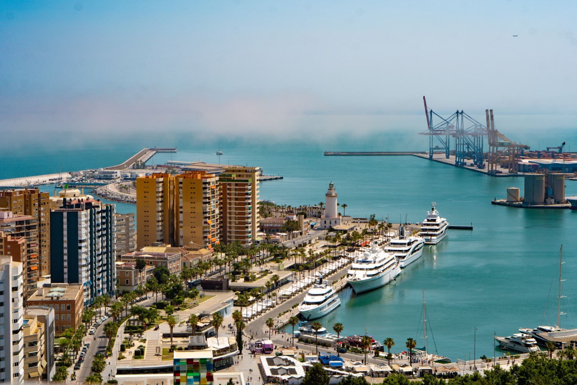 A vibrant aerial view of Málaga city, showcasing its beautiful harbor and urban skyline under a clear blue sky.