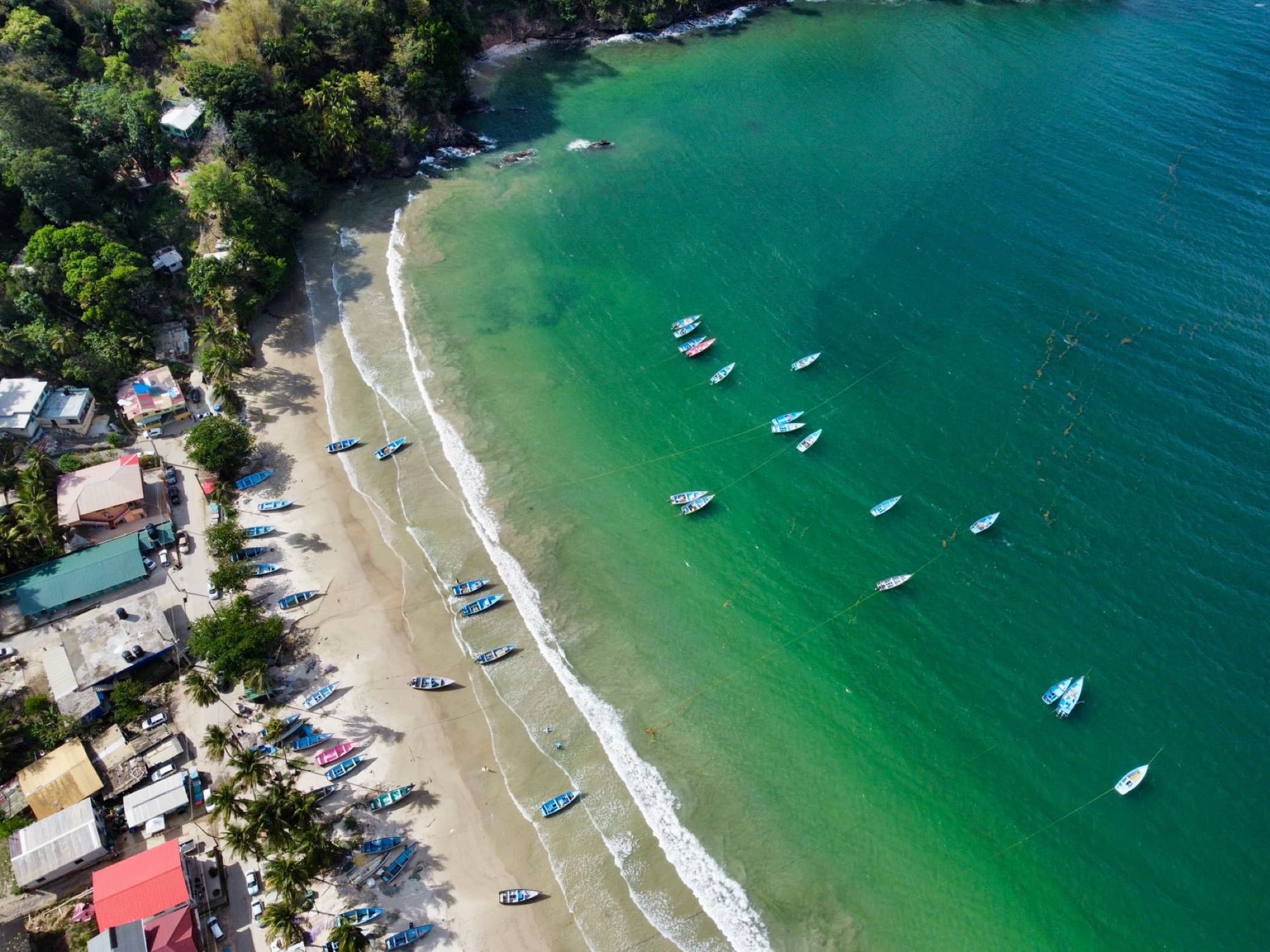 Aerial shot of a vibrant tropical beach with boats along the shoreline.