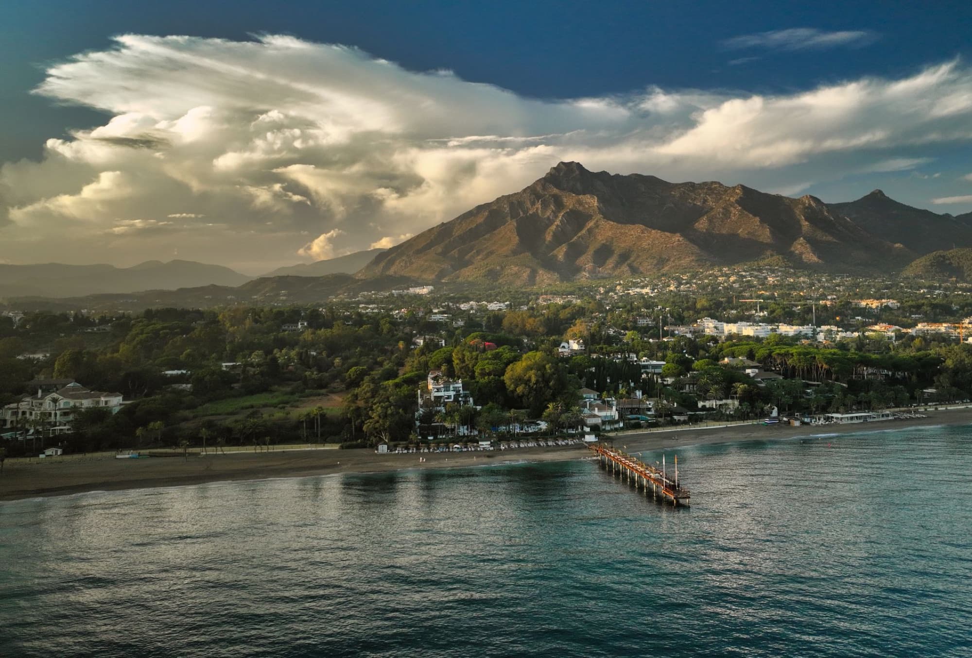 A breathtaking aerial view of Marbella's coastline, lush greenery, and majestic mountains.