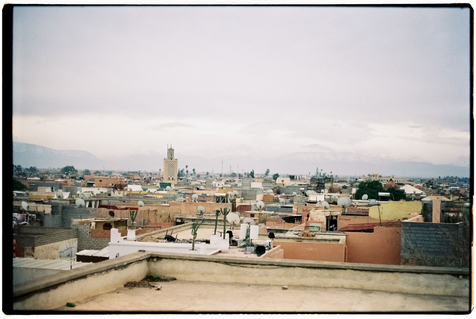 Explore the rustic rooftops of Marrakech with the majestic Atlas Mountains in the distance.