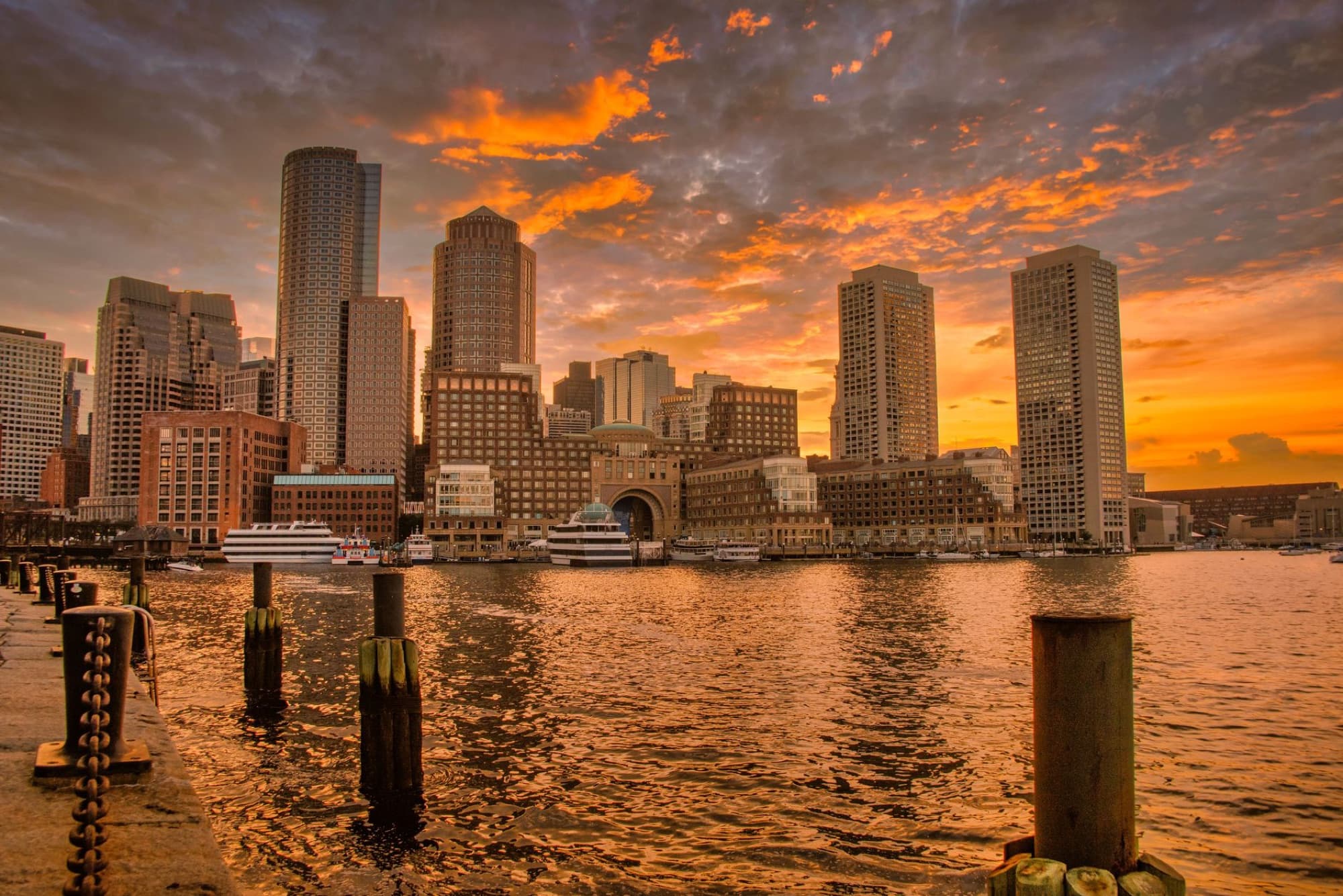 Stunning sunset over Boston's iconic skyline reflecting in the harbor waters.