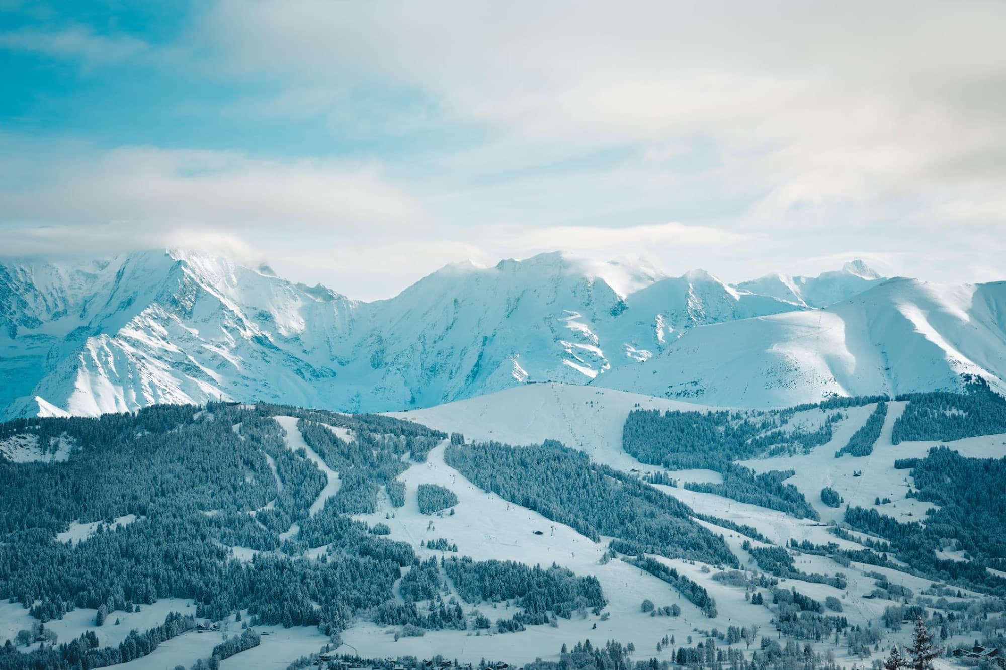 A serene winter landscape showcasing snow-covered mountains and forests in Megève, France.