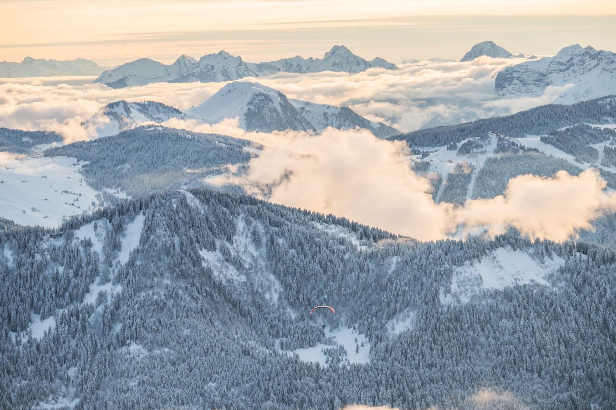A breathtaking aerial view of snow-covered mountains and forests during winter.
