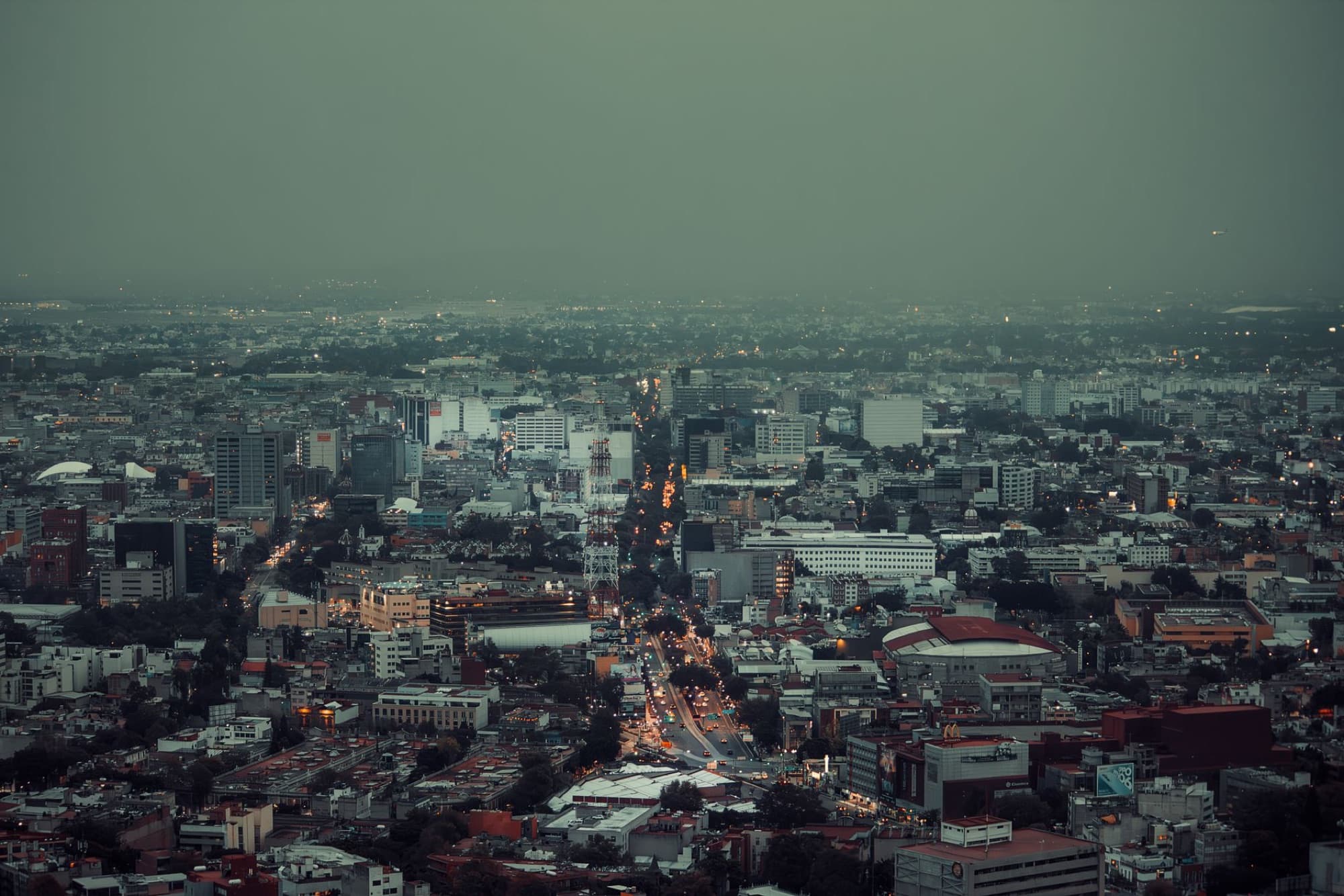 Aerial cityscape of Mexico City showcasing urban architecture and sprawling city lights after sunset.