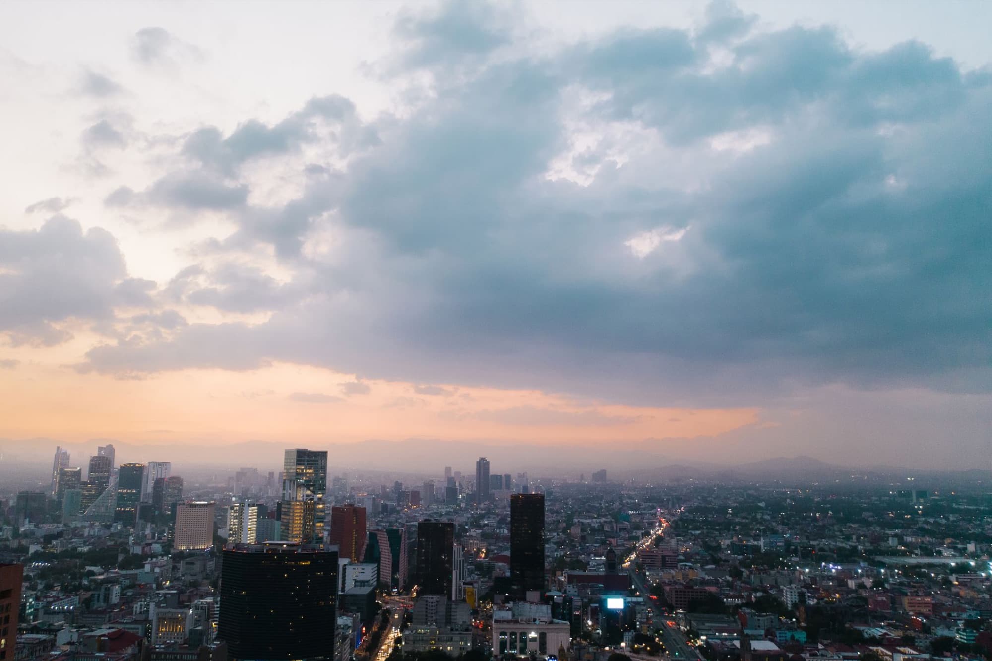 Captivating aerial view of Mexico City skyline at dusk, featuring modern skyscrapers and vibrant urban landscape.