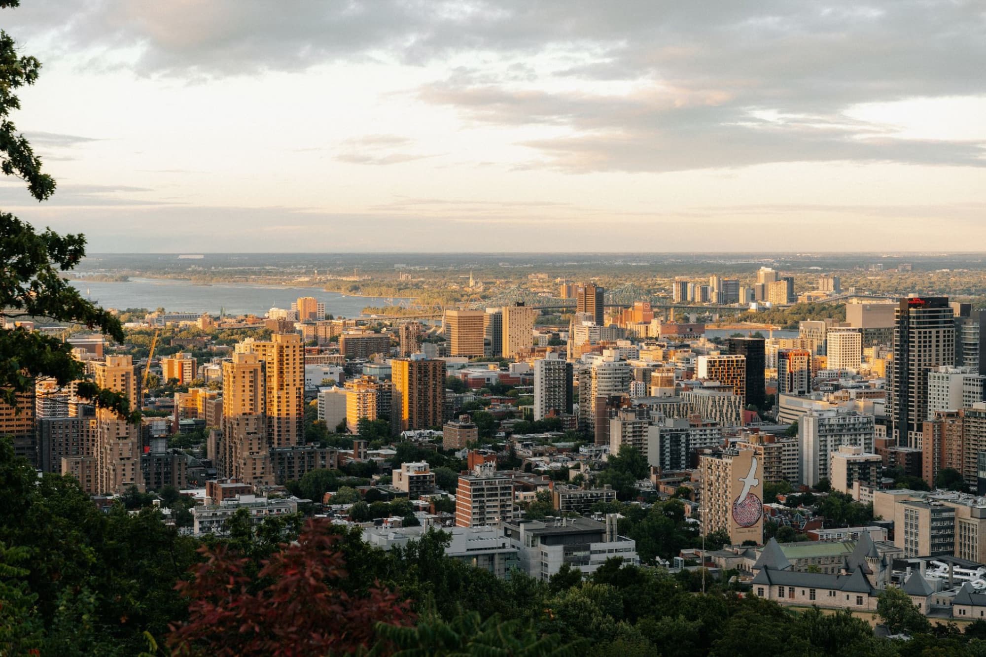 A breathtaking aerial view of Montréal's skyline during sunset with vibrant city lights and lush surroundings.