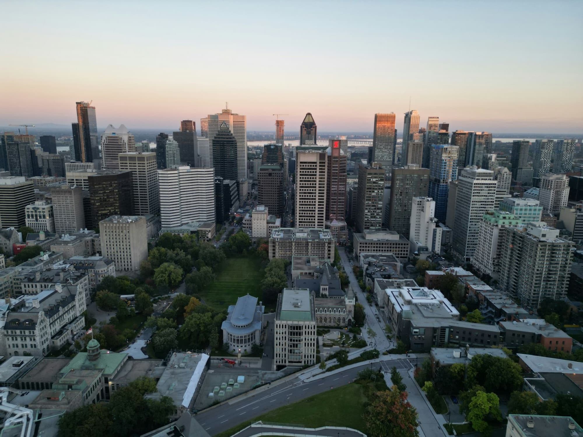 A panoramic aerial view of Montreal's skyline at sunset with cityscape and greenery.