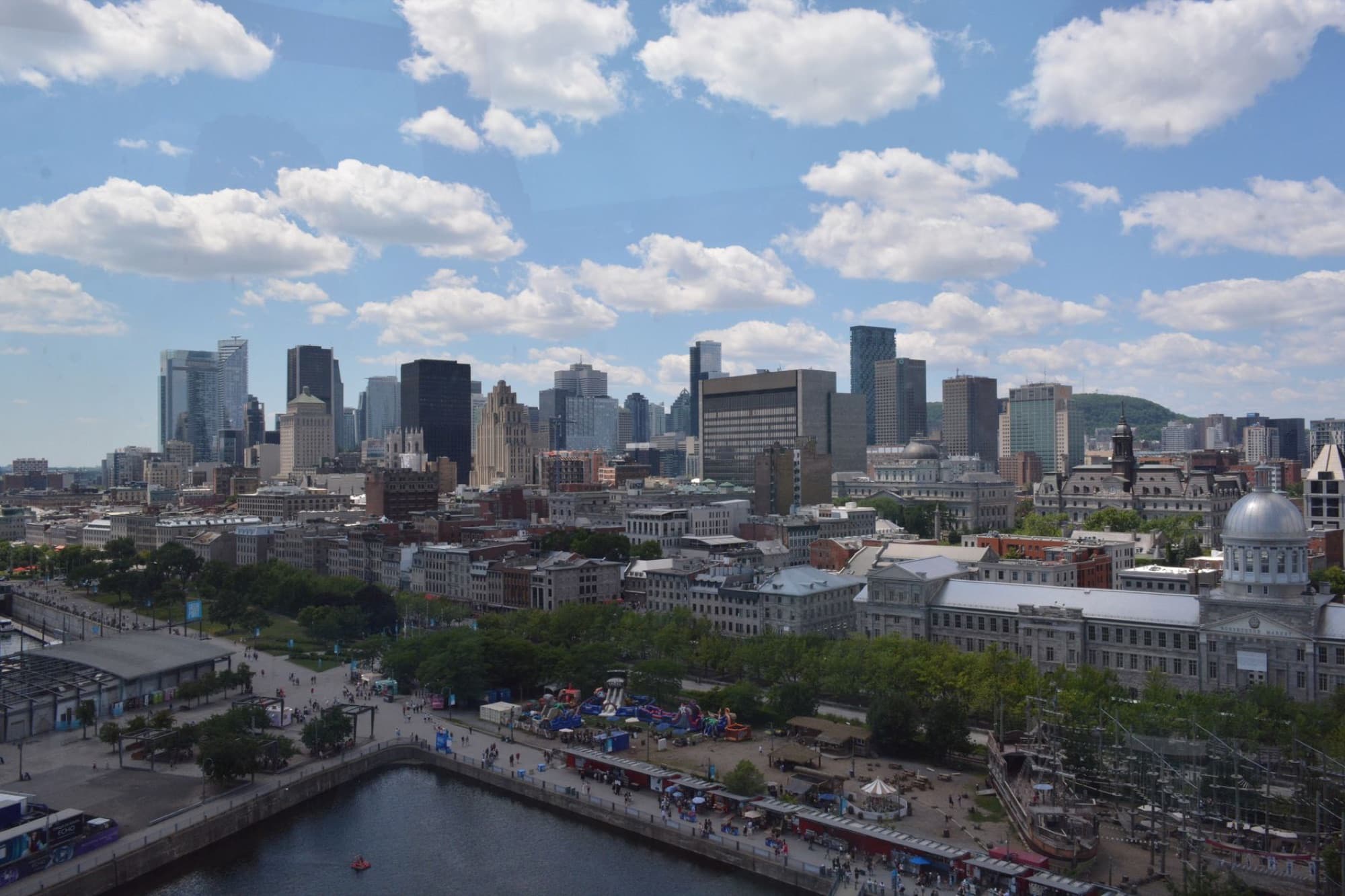 Aerial view of Montreal's skyline under a bright blue sky with fluffy clouds.