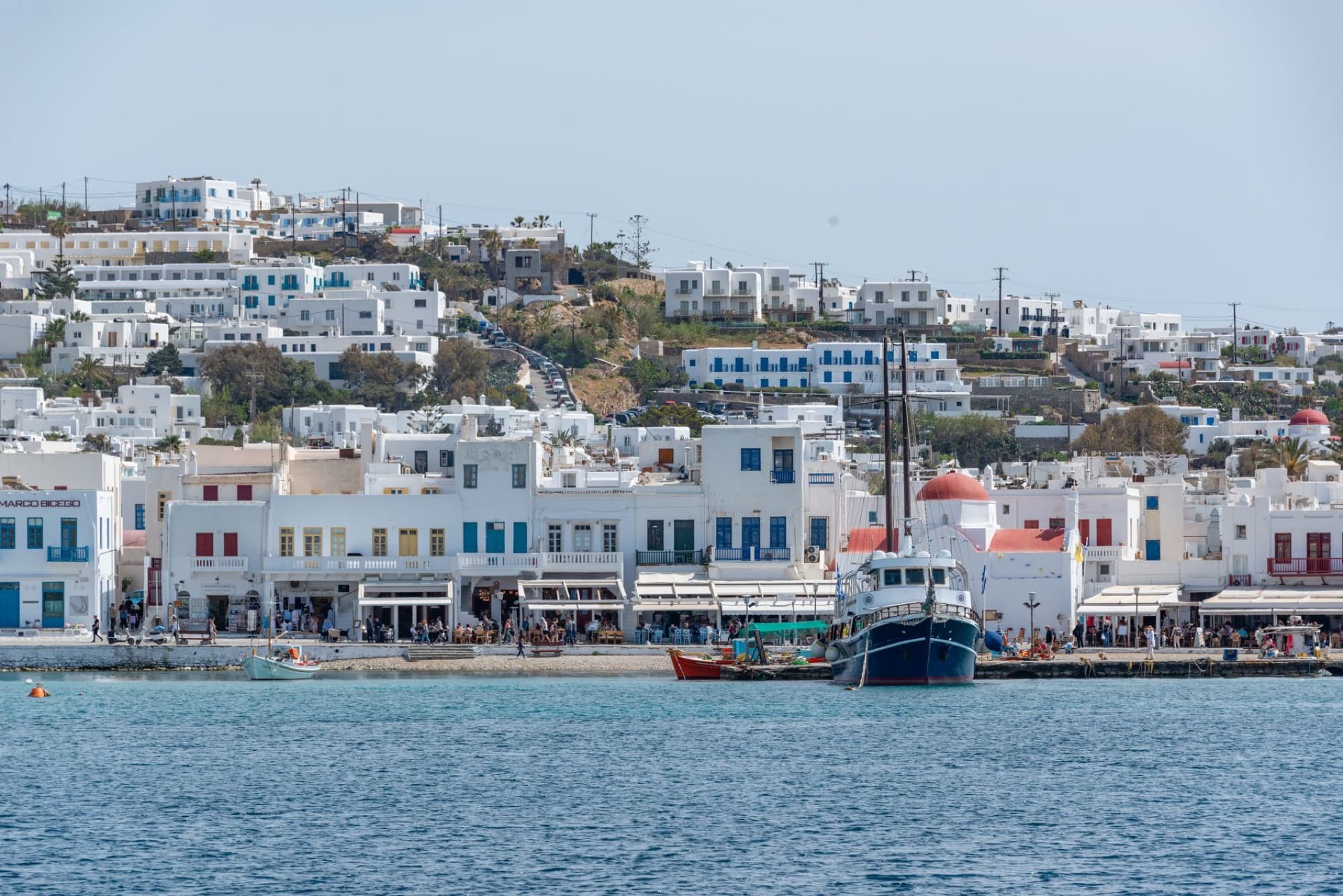 Picturesque view of Mykonos Town with traditional white buildings and boats in the harbor.