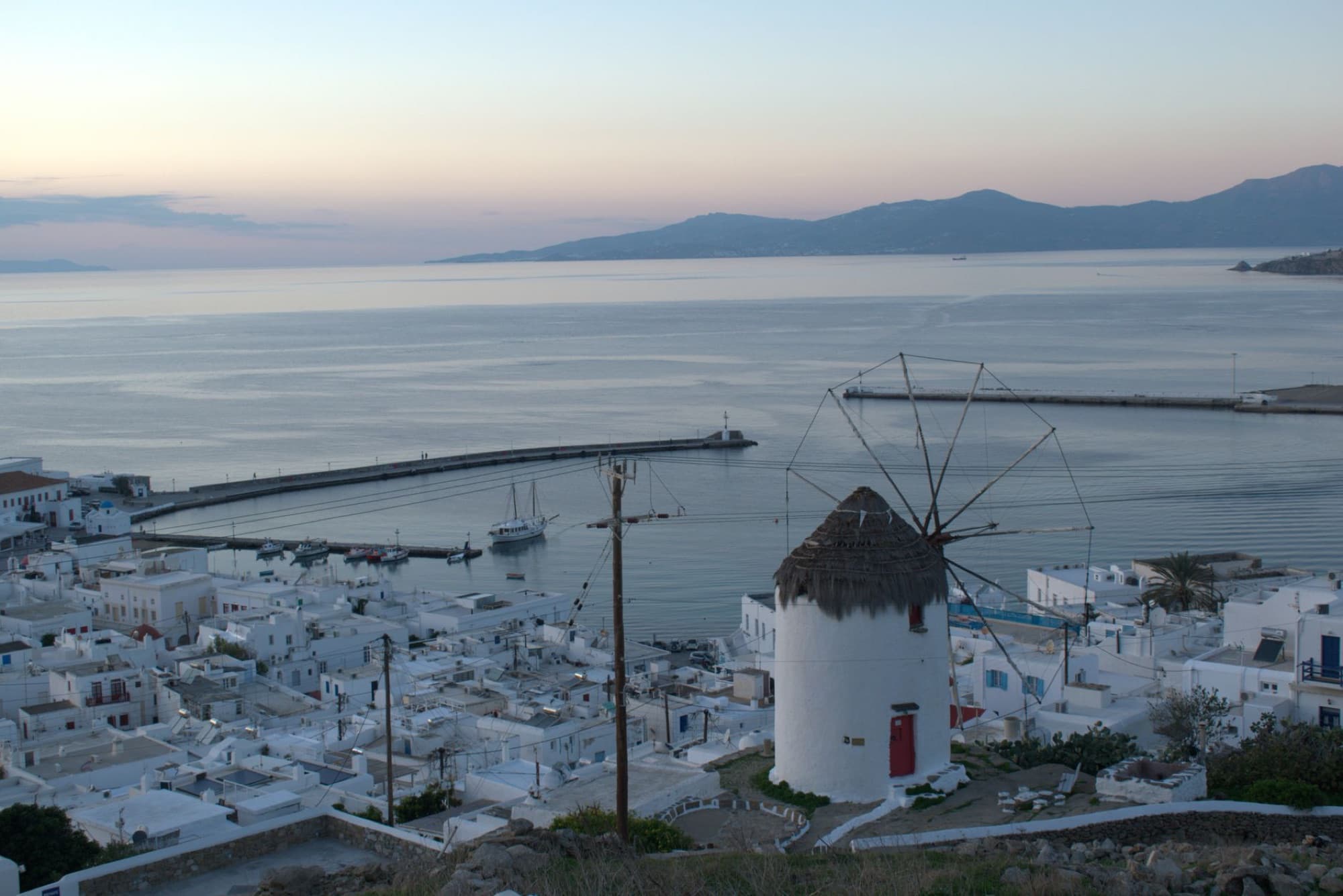 Stunning aerial view of a windmill and coast in Mykonos, Greece at dusk.